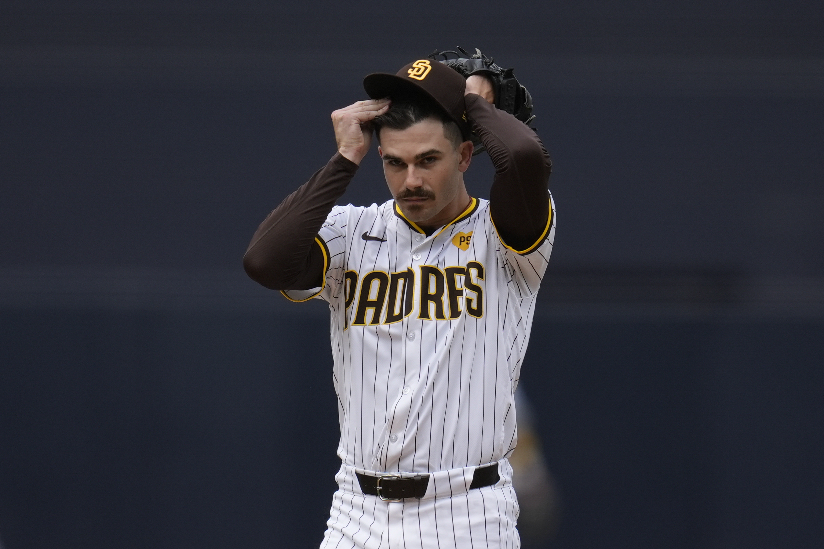 San Diego Padres starting pitcher Dylan Cease adjusts his hat as he works against a Houston Astros batter during the first inning of a baseball game Wednesday, Sept. 18, 2024, in San Diego.