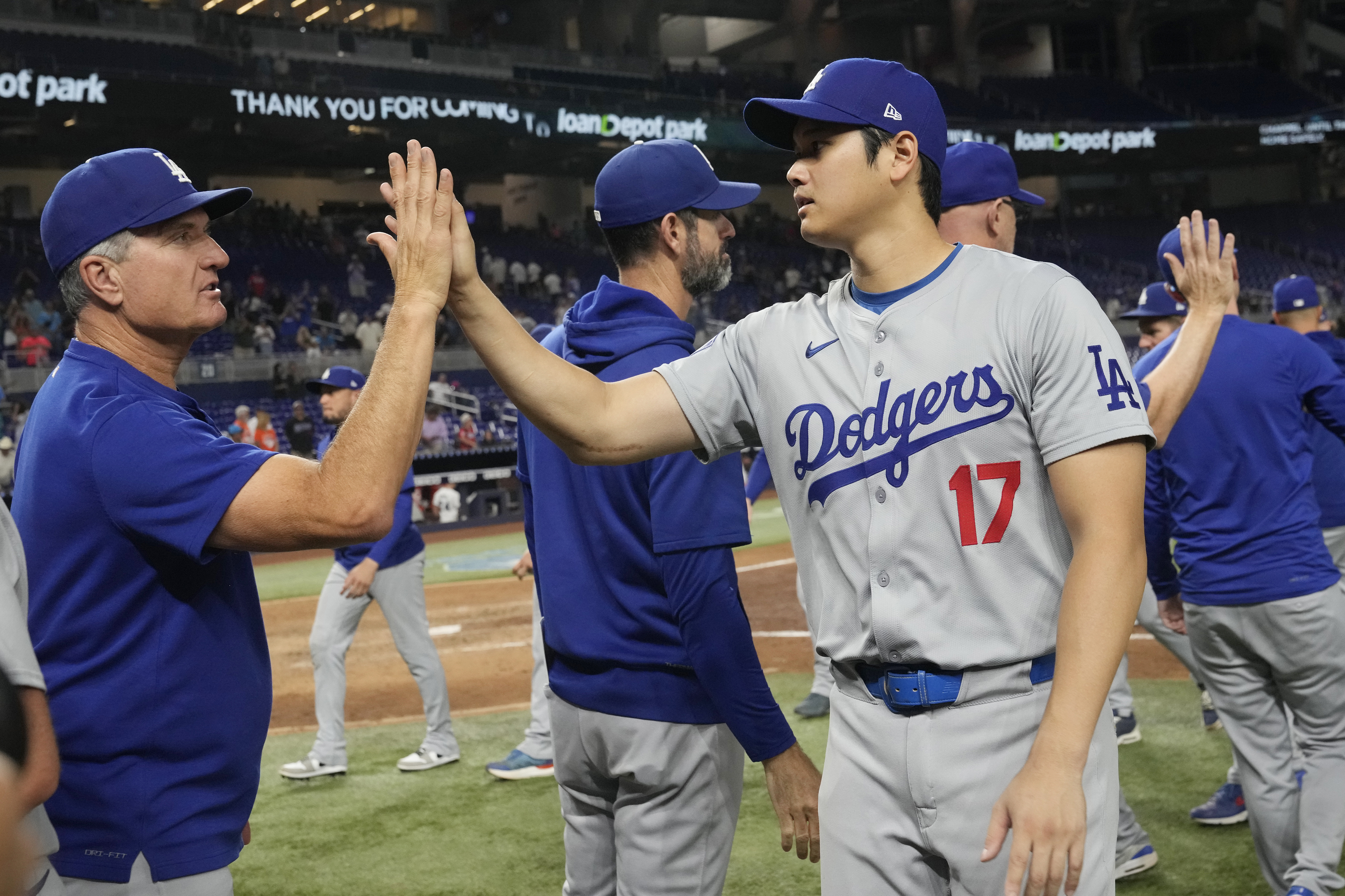 Los Angeles Dodgers' Shohei Ohtani (17) is congratulated by a coach at the end of a baseball game against the Miami Marlins, Thursday, Sept. 19, 2024, in Miami.