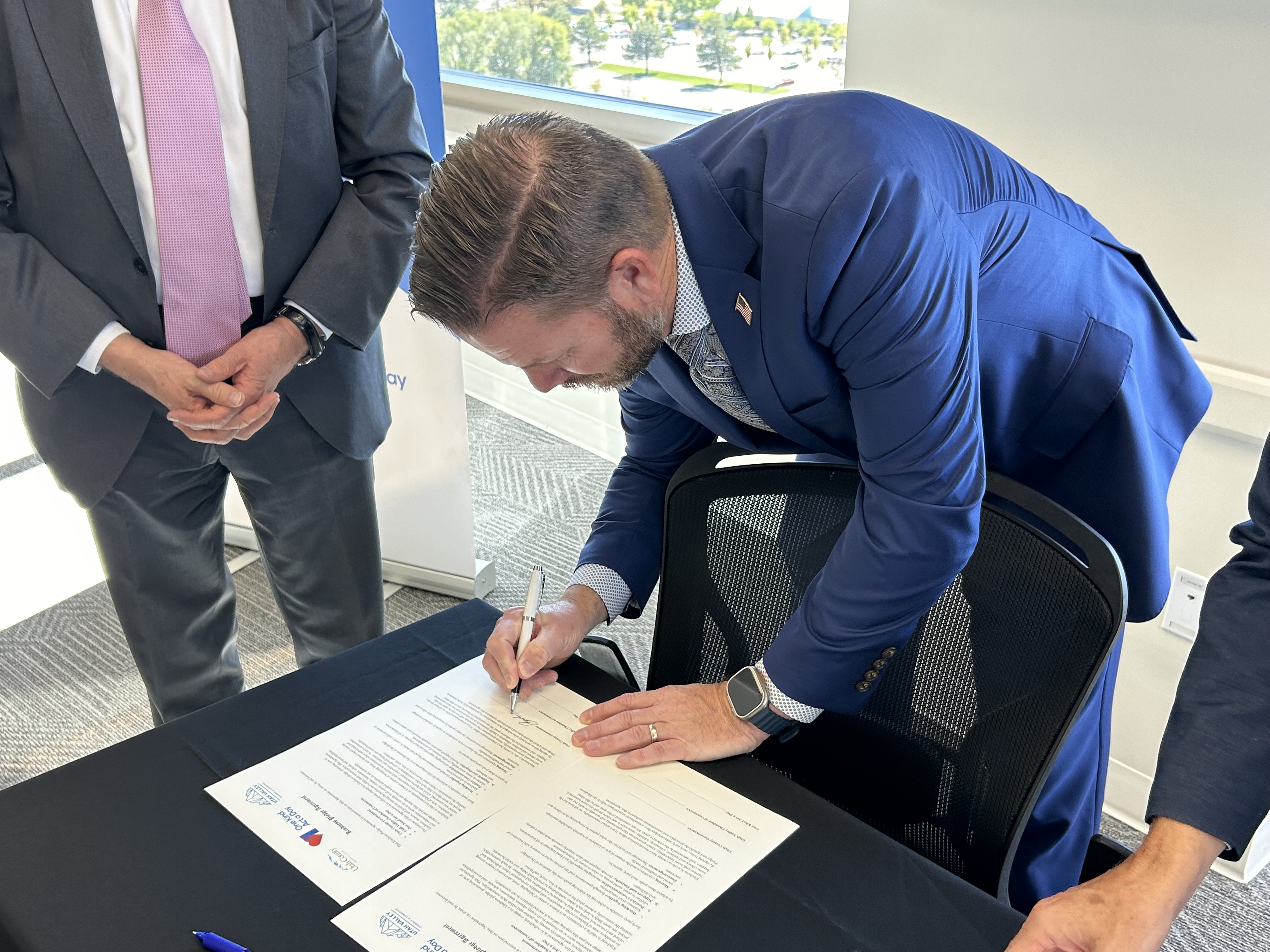 Commissioner Brandon Gordon signs a declaration making Utah County the "first certified county of kindness" at a press conference at Rocky Mountain University Thursday.