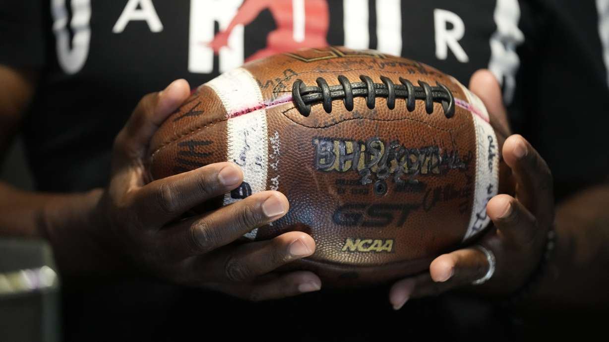 Phillip Laster Sr. holds a football in Brandon, Miss., Tuesday, Aug. 27, 2024, signed by teammates of his son Phillip Laster Jr., that was given to him on senior night after his passing.