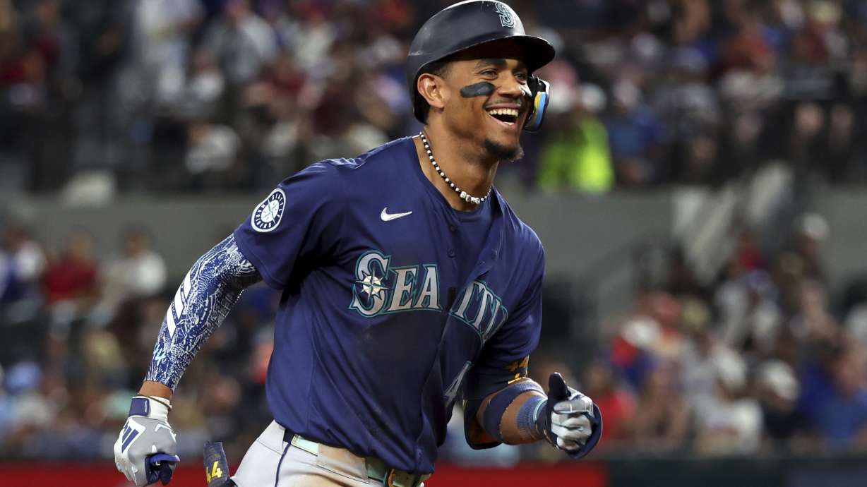 Seattle Mariners' Julio Rodriguez reacts toward the dugout as he runs the bases after hitting a two-run home run against the Texas Rangers in the seventh inning, Friday, Sept. 20, 2024, in Arlington, Texas.