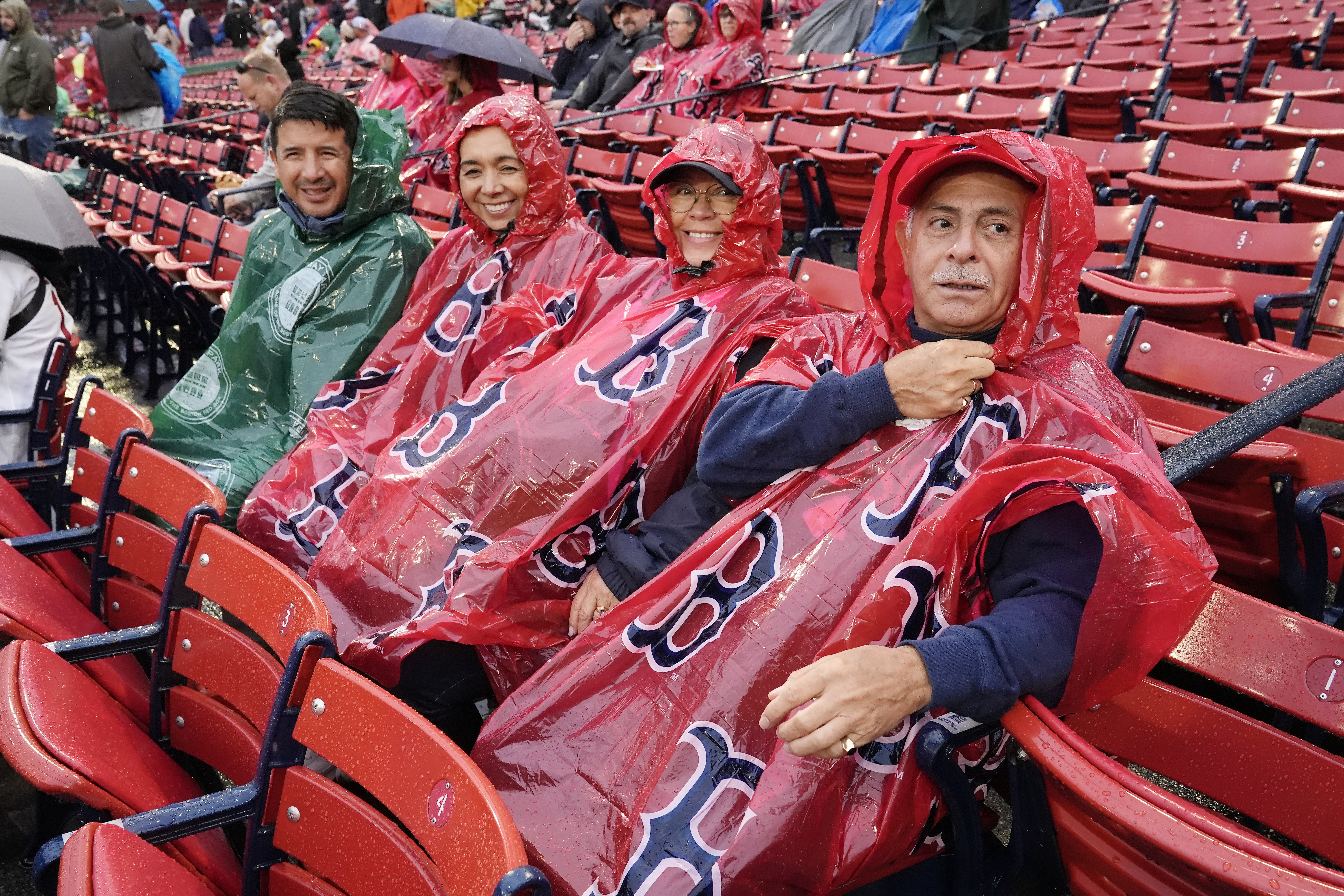 Fans wait in the rain before a baseball game between the Boston Red Sox and the Minnesota Twins, Saturday, Sept. 21, 2024, in Boston. The game was postponed to Sunday as part of a day/night doubleheader. 
