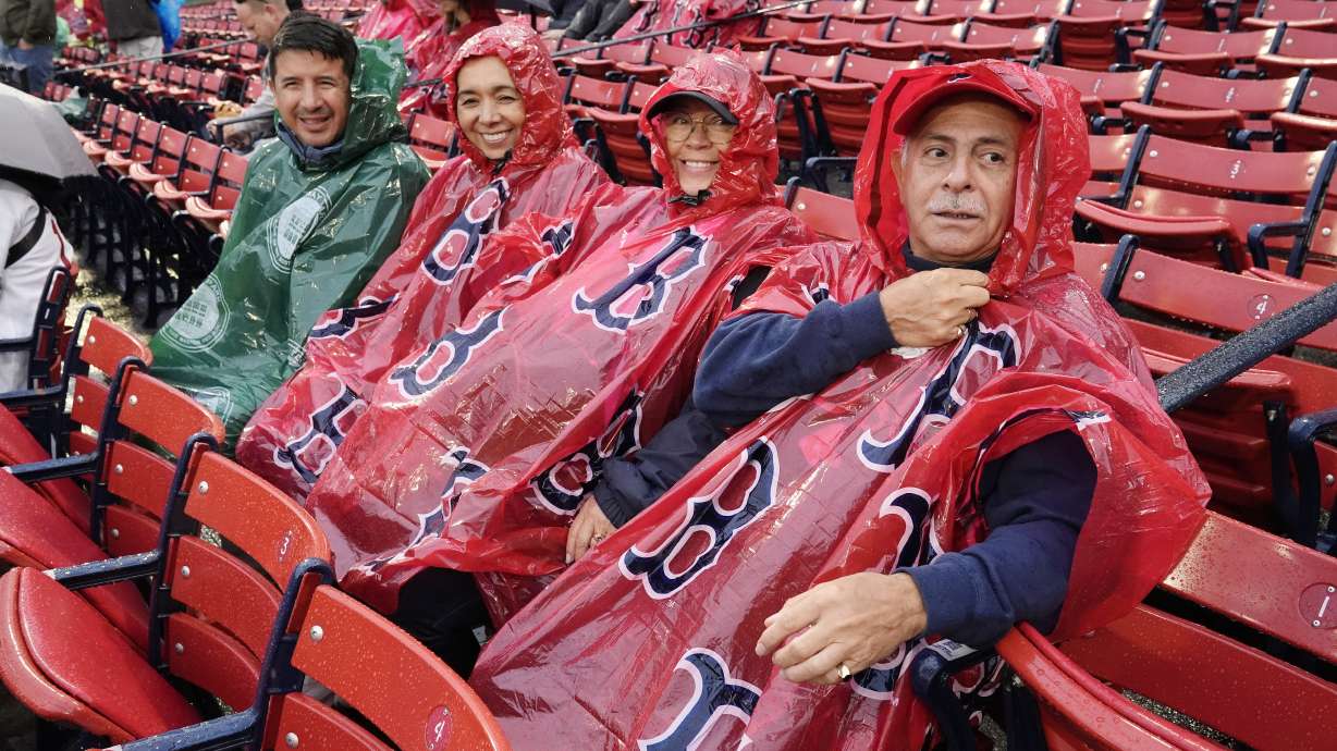 Fans wait in the rain before a baseball game between the Boston Red Sox and the Minnesota Twins, Saturday, Sept. 21, 2024, in Boston. The game was postponed to Sunday as part of a day/night doubleheader.
