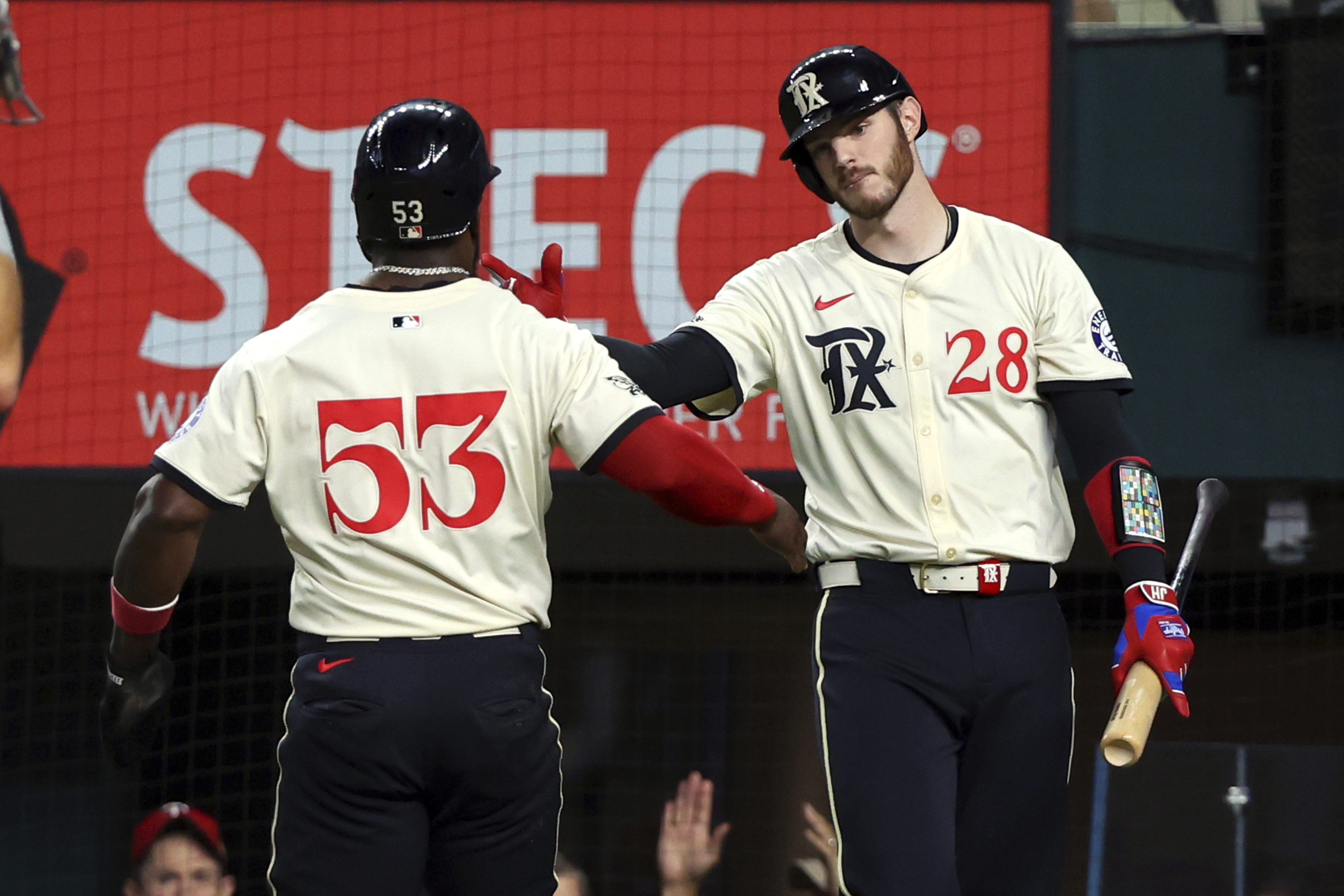 Texas Rangers' Adolis Garcia (53) celebrates with Jonah Heim (28) after scoring on a single by Nathaniel Lowe in the fourth inning of a baseball game against the Seattle Mariners, Friday, Sept. 20, 2024, in Arlington, Texas.