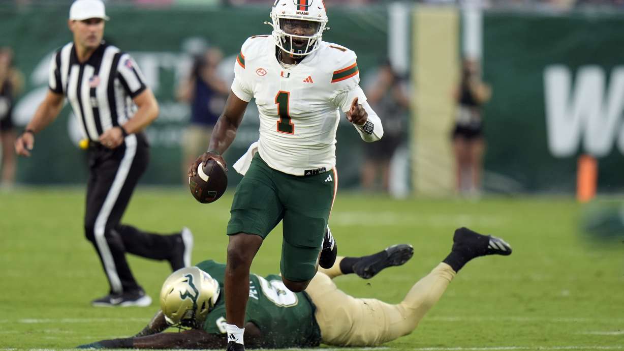 Miami quarterback Cam Ward (1) scrambles away from South Florida linebacker Jamie Pettway during the first half of an NCAA college football game Saturday, Sept. 21, 2024, in Tampa, Fla.