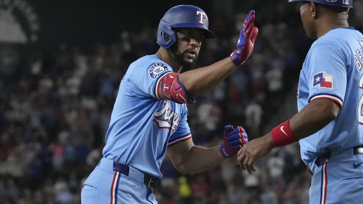 Texas Rangers' Leody Taveras, left, is congratulated by third base coach Tony Beasley, right, after hitting a home run during the seventh inning of a baseball game against the Seattle Mariners, Sunday, Sept. 22, 2024, in Arlington, Texas.
