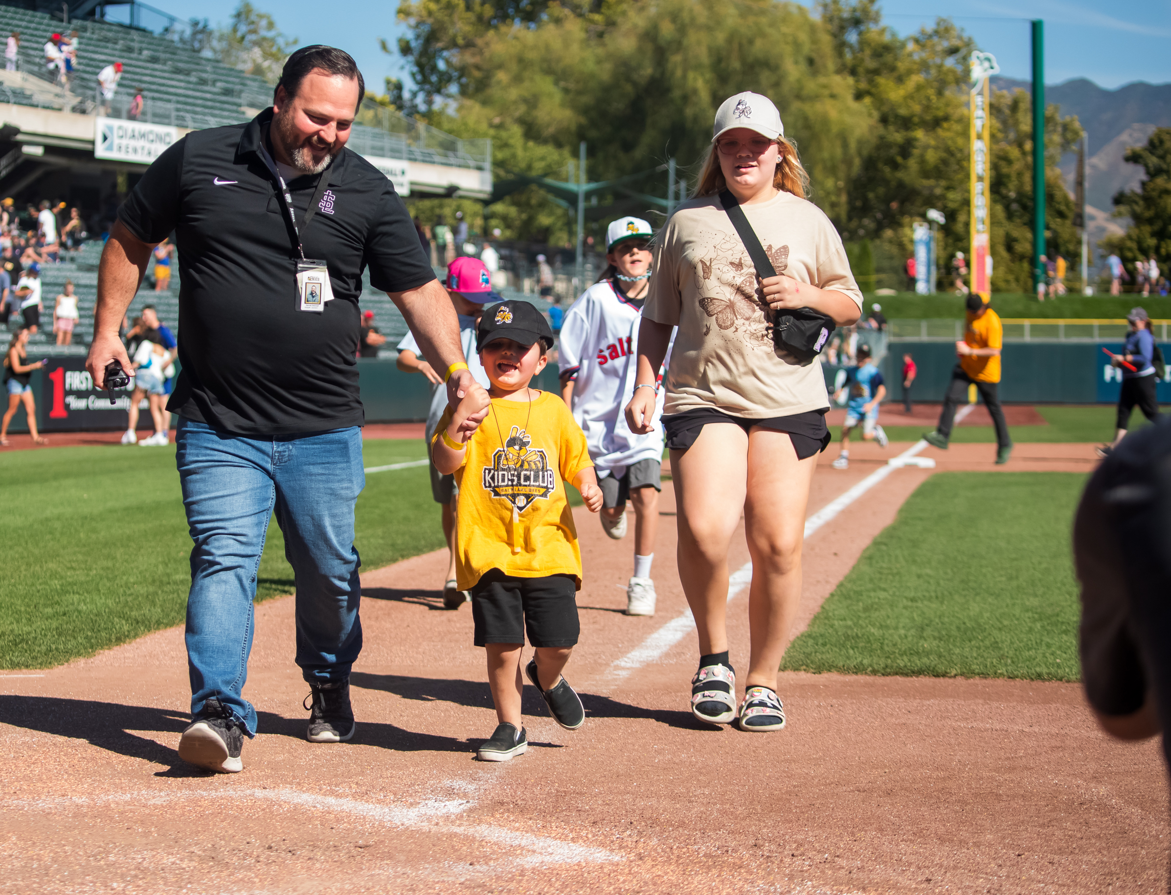 Fans run around the bases of Smith's Ballpark after the team's last game at the stadium on Sunday.