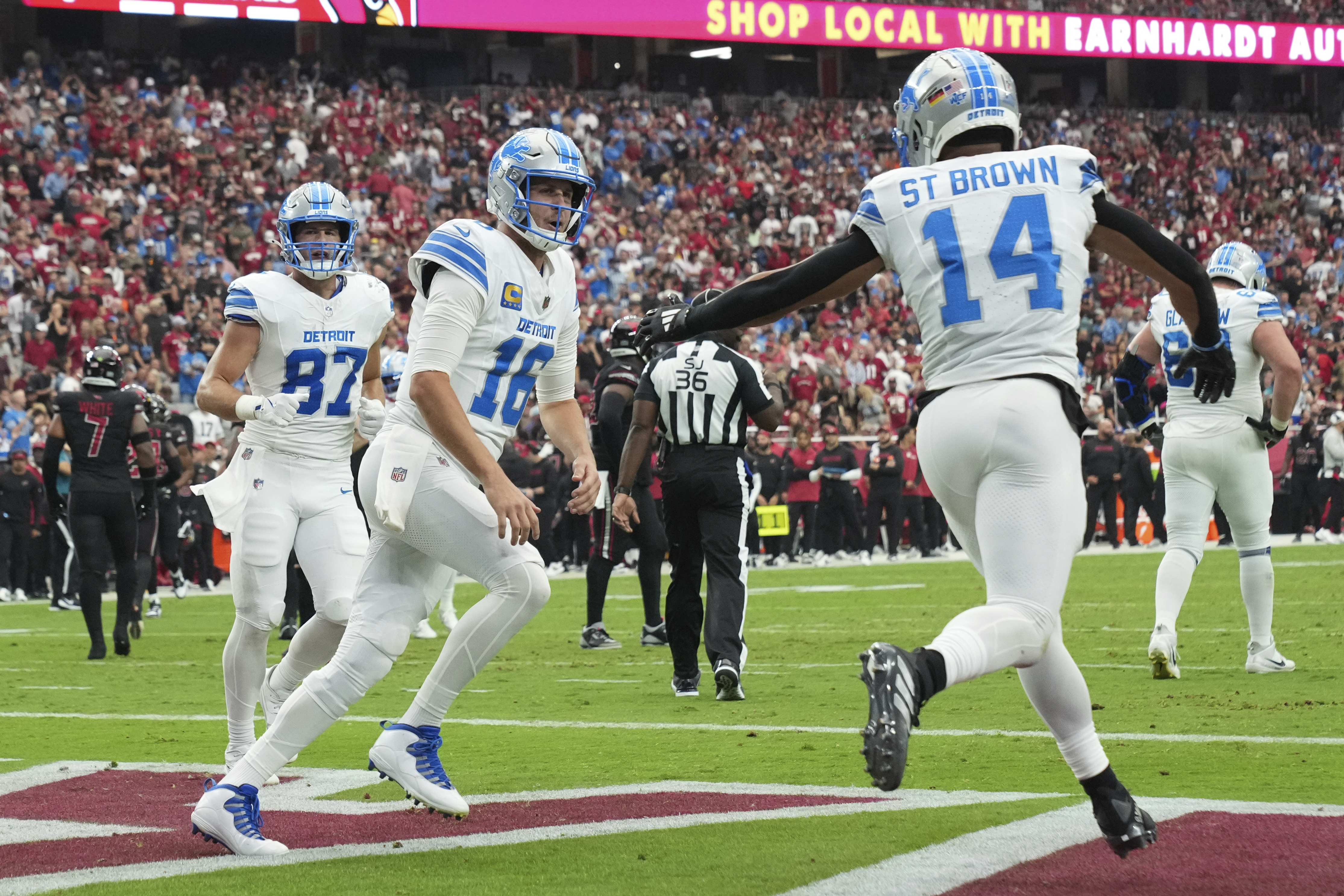 Detroit Lions wide receiver Amon-Ra St. Brown (14) celebrates his five-yard touchdown reception with quarterback Jared Goff (16) during the first half of an NFL football game against the Arizona Cardinals Sunday, Sept. 22, 2024, in Glendale, Ariz. 