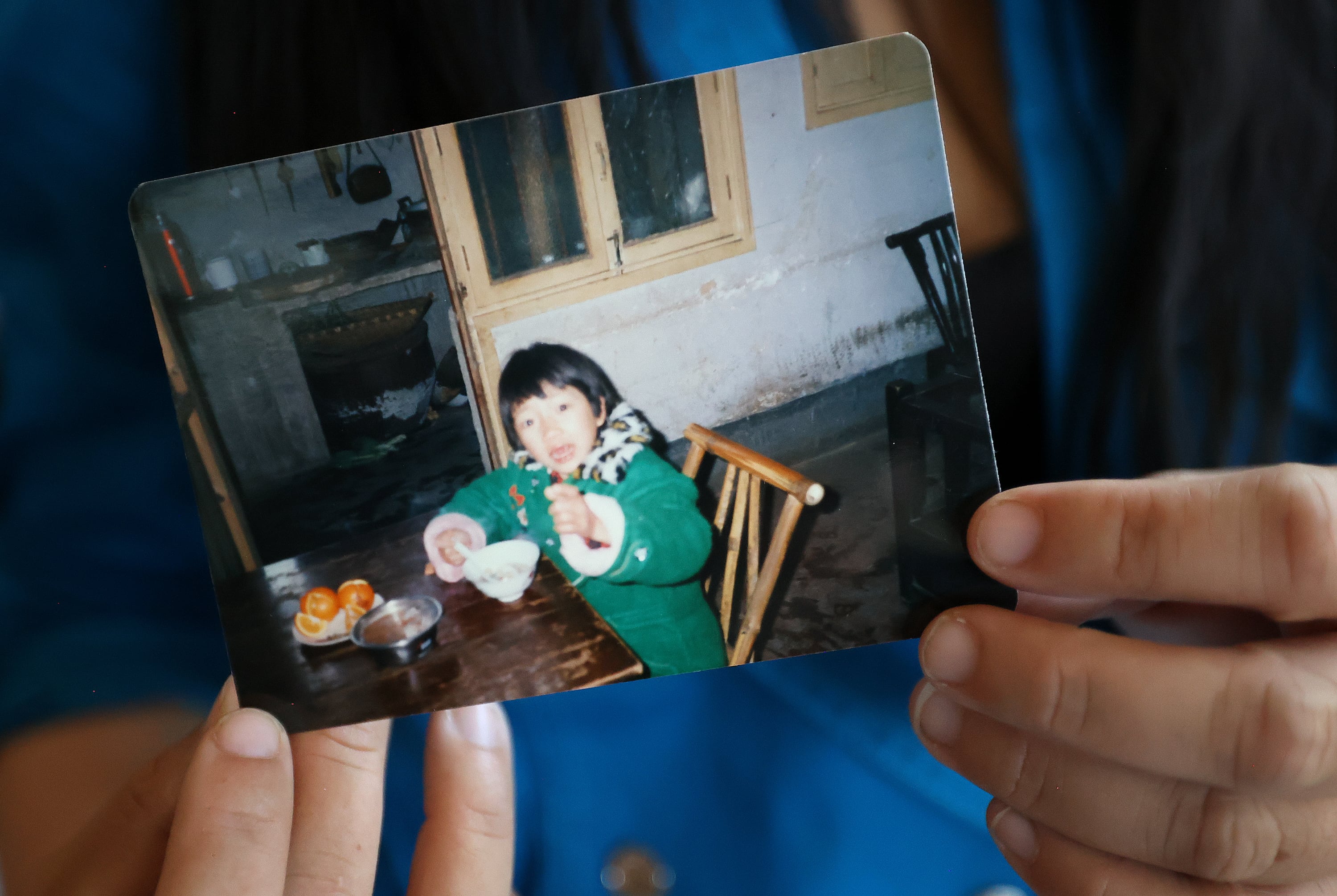 Amy Sunderland holds a photo of her as a child in Hunan Province, China, while at home as an adult in Millcreek on Sept. 12.