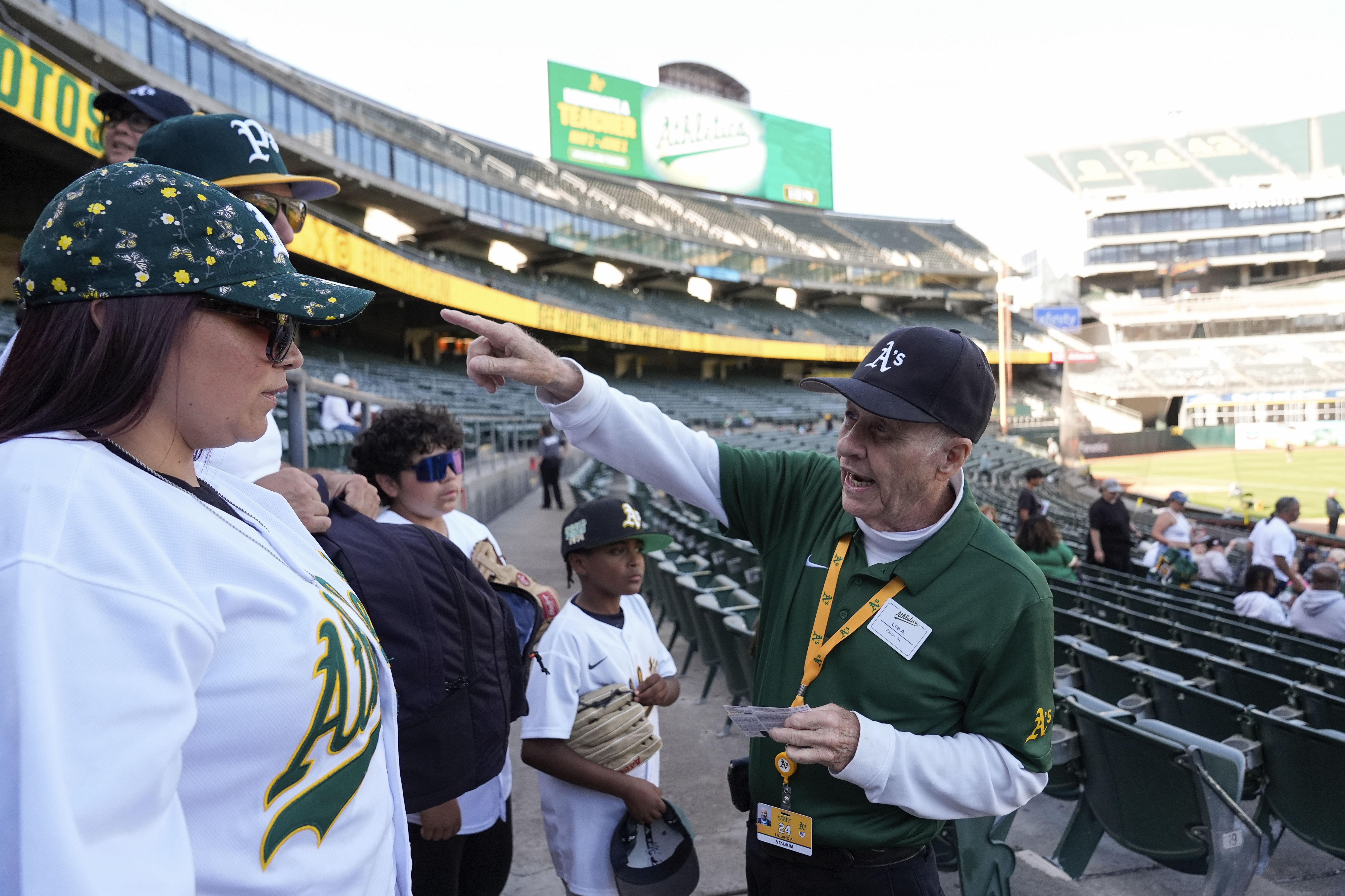 Leland Anderson, right, speaks with fans attending a baseball game between the Colorado Rockies and the Oakland Athletics, Wednesday, May 22, 2024, in Oakland, Calif.