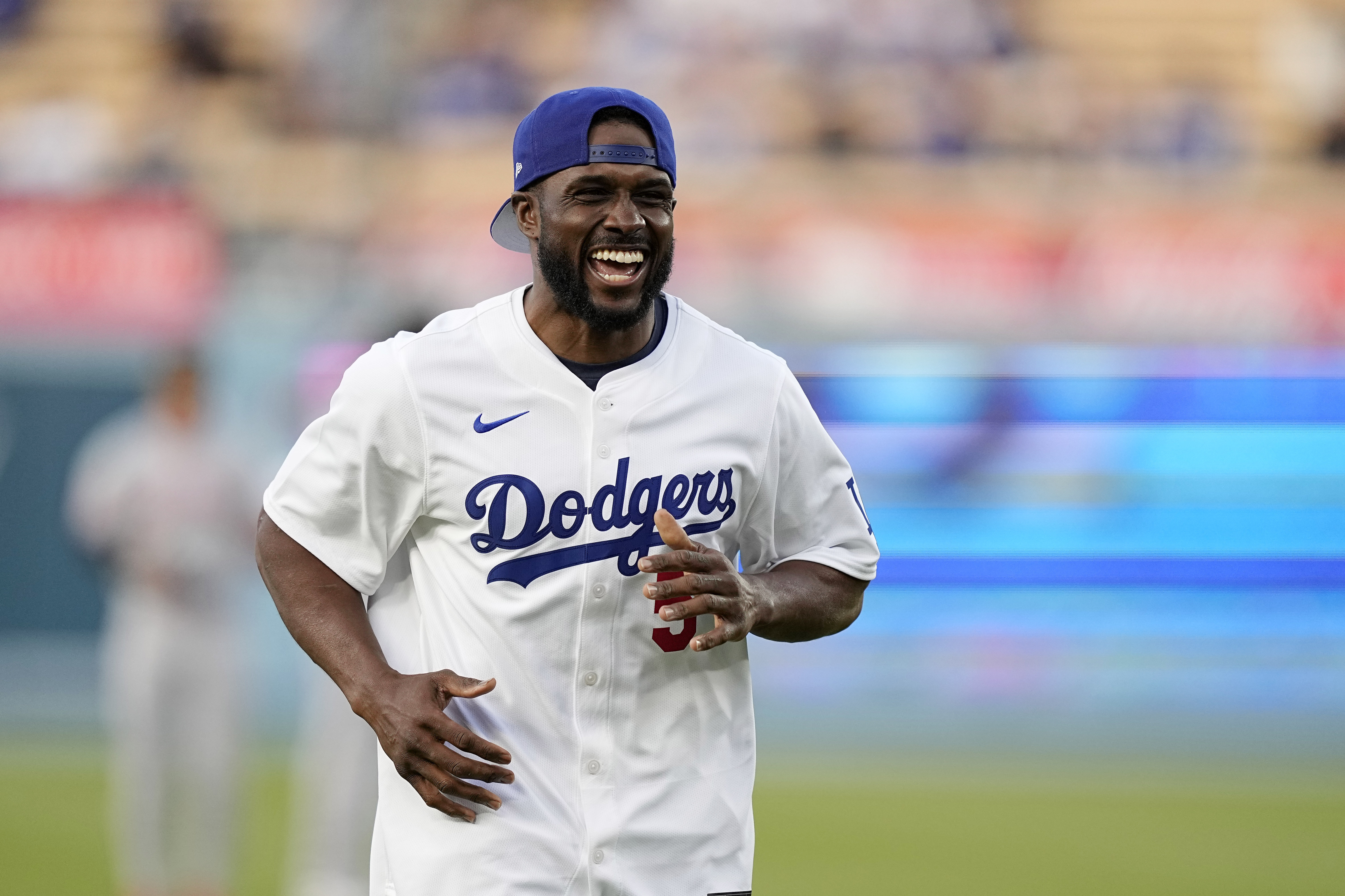 FILE - Former NFL and University of Southern California running back Reggie Bush, left, jokes with laughs after throwing out the ceremonial first pitch prior to a baseball game between the Los Angeles Dodgers and the Cincinnati Reds Friday, May 17, 2024, in Los Angeles. 