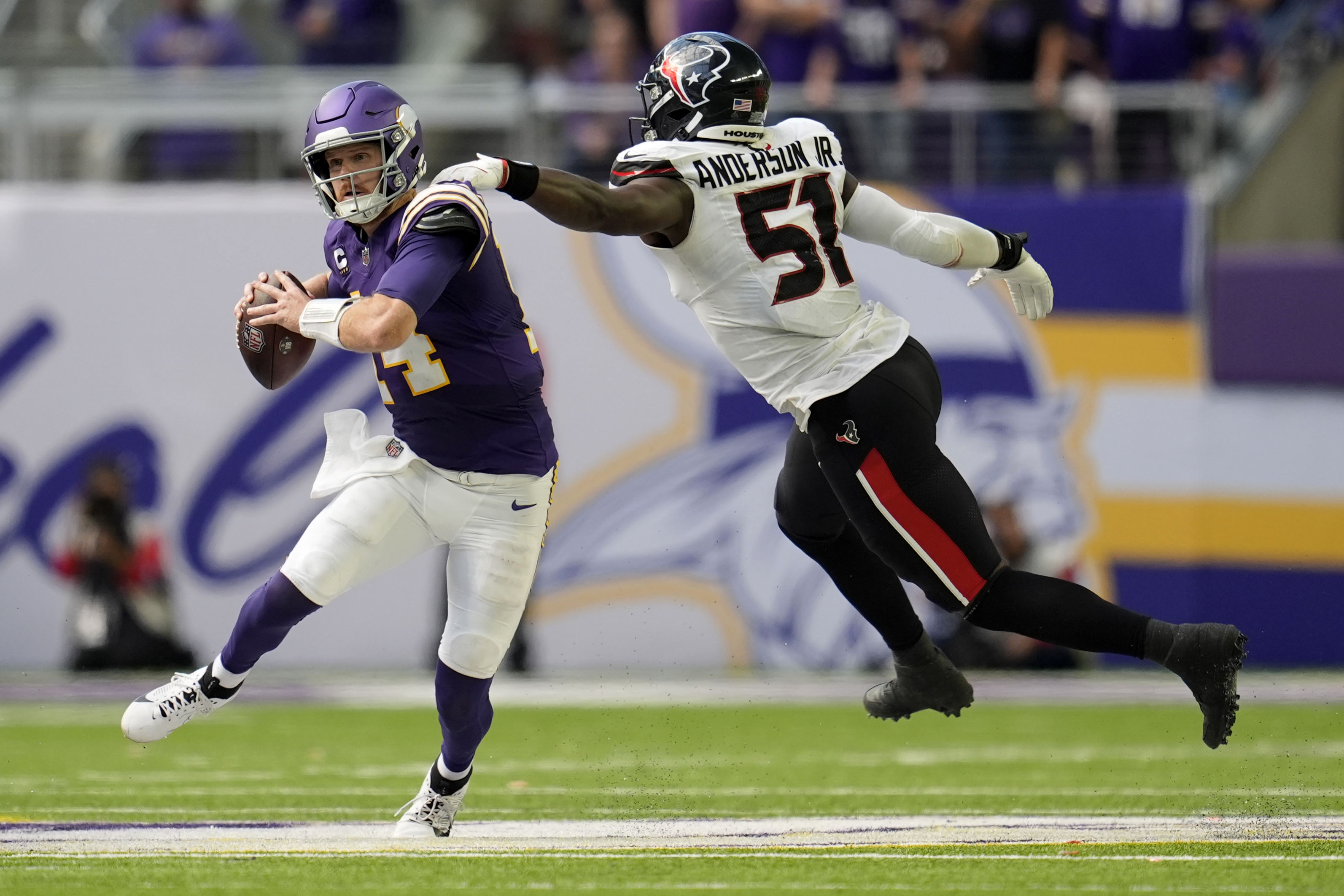 Minnesota Vikings quarterback Sam Darnold (14) runs from Houston Texans defensive end Will Anderson Jr. (51) during the second half of an NFL football game, Sunday, Sept. 22, 2024, in Minneapolis. 