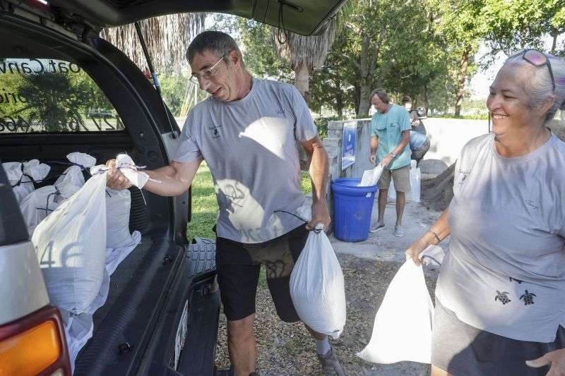 Karl Bohlmann, left, and Tangi Bohlmann, of Tarpon Springs, collect sandbags at a public site while residents prepare their homes for potential flooding, Tuesday in Tarpon Springs, Fla., as Tropical Storm Helene approaches.