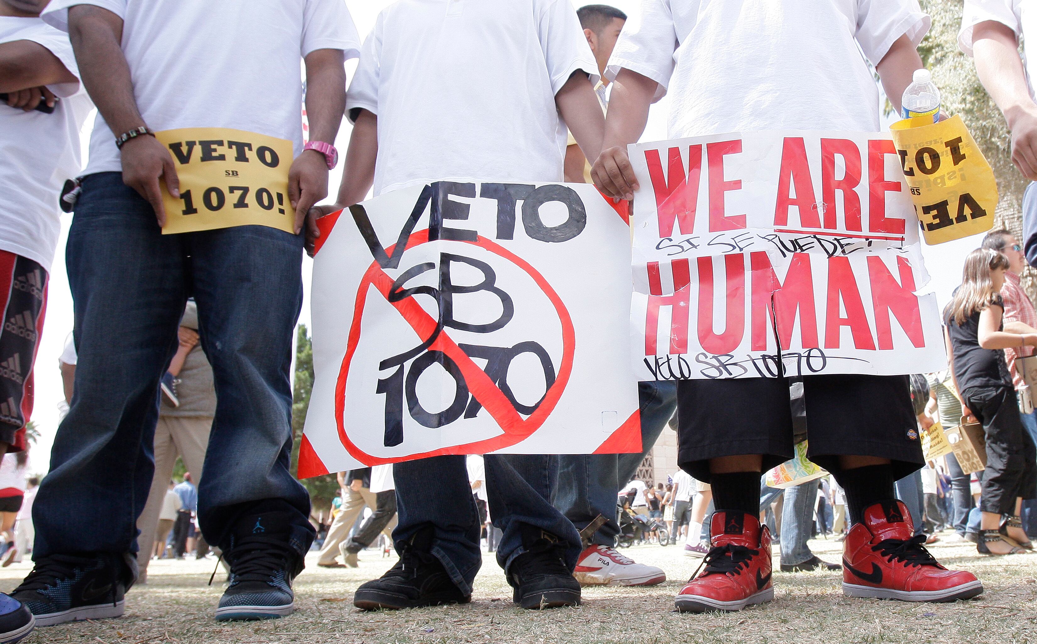 Protesters hold signs at a 2010 rally at the Arizona Capitol prior to former Arizona Gov. Jan Brewer signing SB1070 into law.