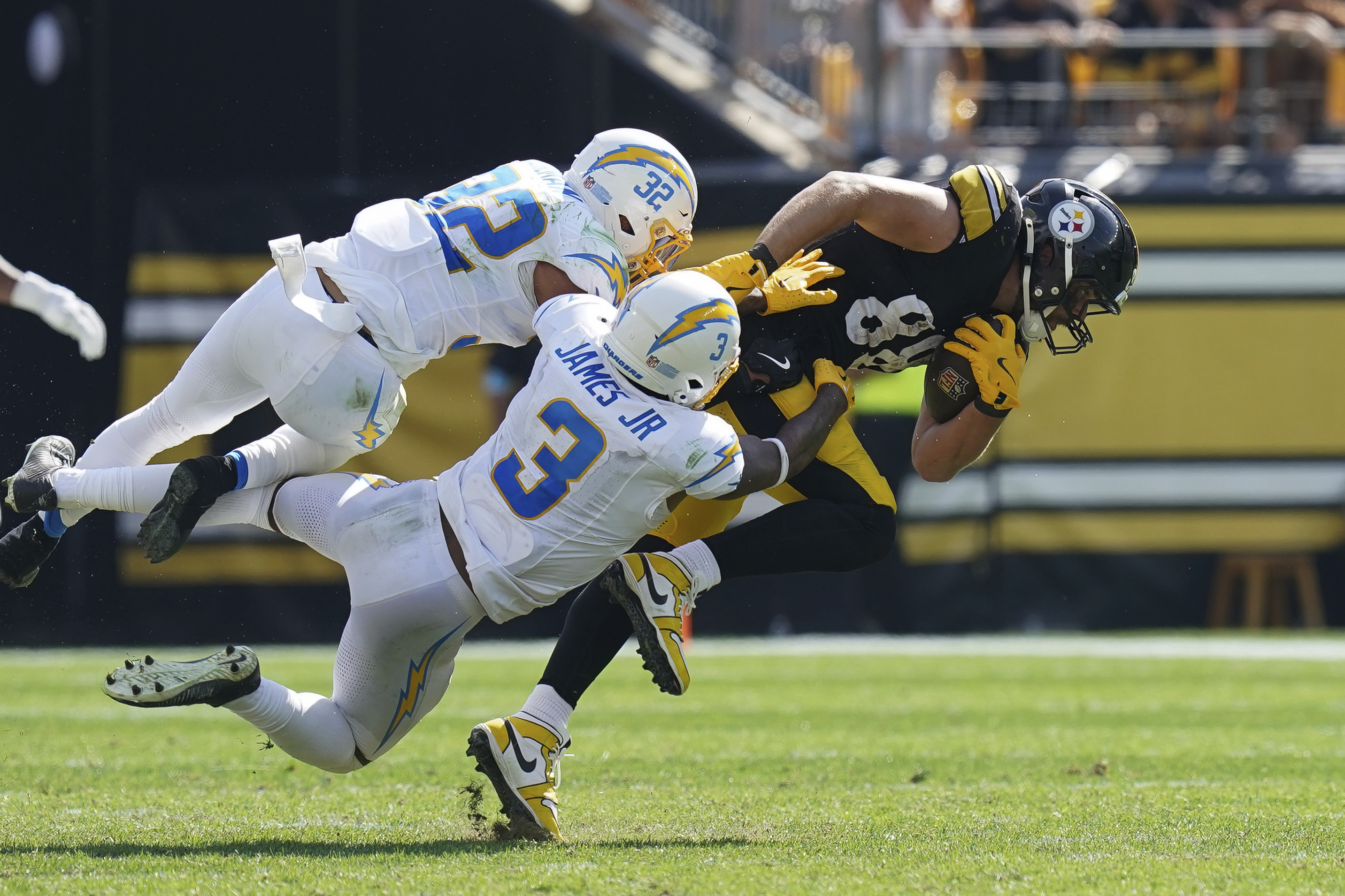 Pittsburgh Steelers tight end Pat Freiermuth, right, is tackled by Los Angeles Chargers safeties Alohi Gilman (32) and Derwin James Jr. during the second half of an NFL football game, Sunday, Sept. 22, 2024, in Pittsburgh. 
