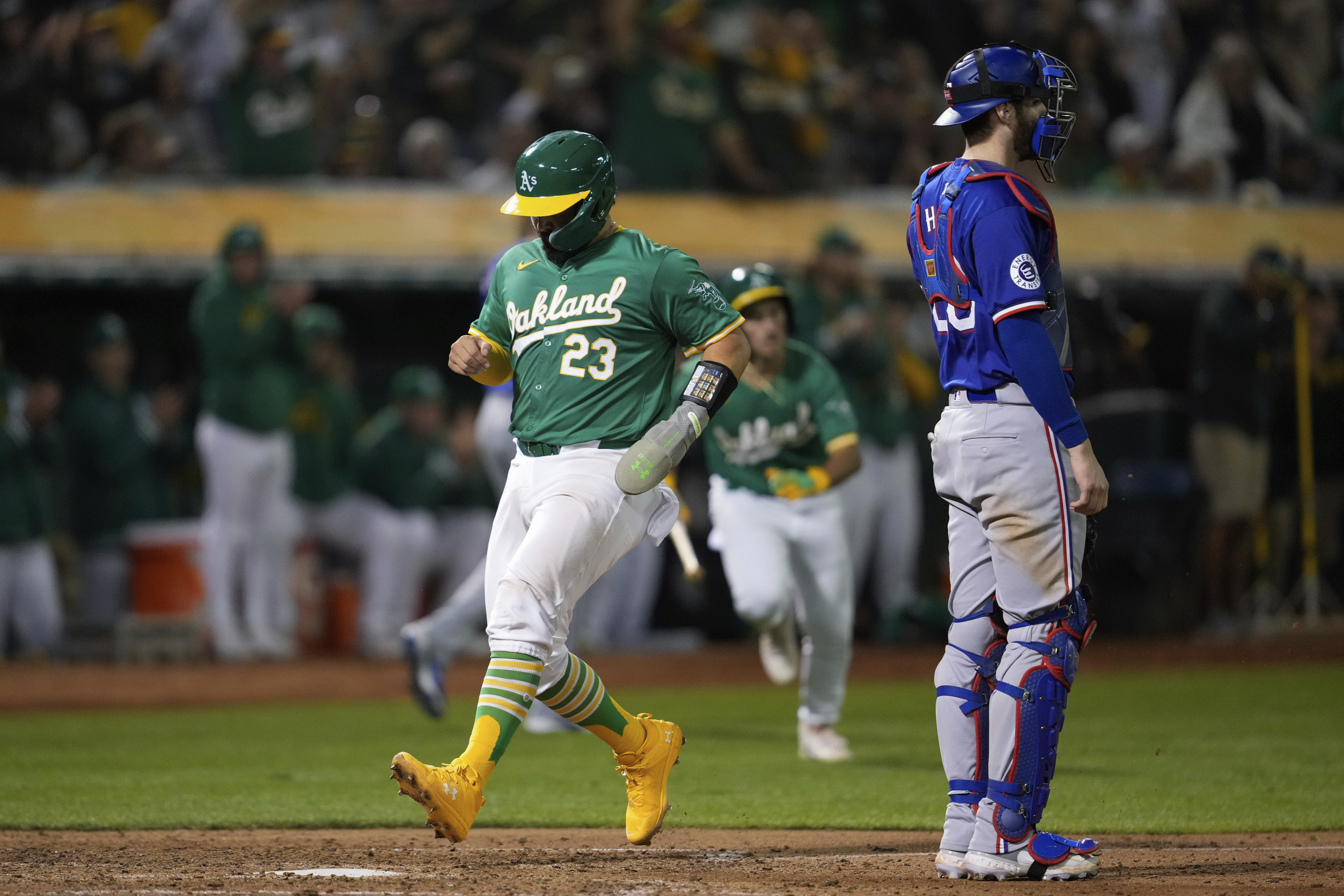 Oakland Athletics' Shea Langeliers (23) scores next to Texas Rangers catcher Jonah Heim on Zack Gelof's sacrifice fly during the sixth inning of a baseball game Tuesday, Sept. 24, 2024, in Oakland, Calif. 