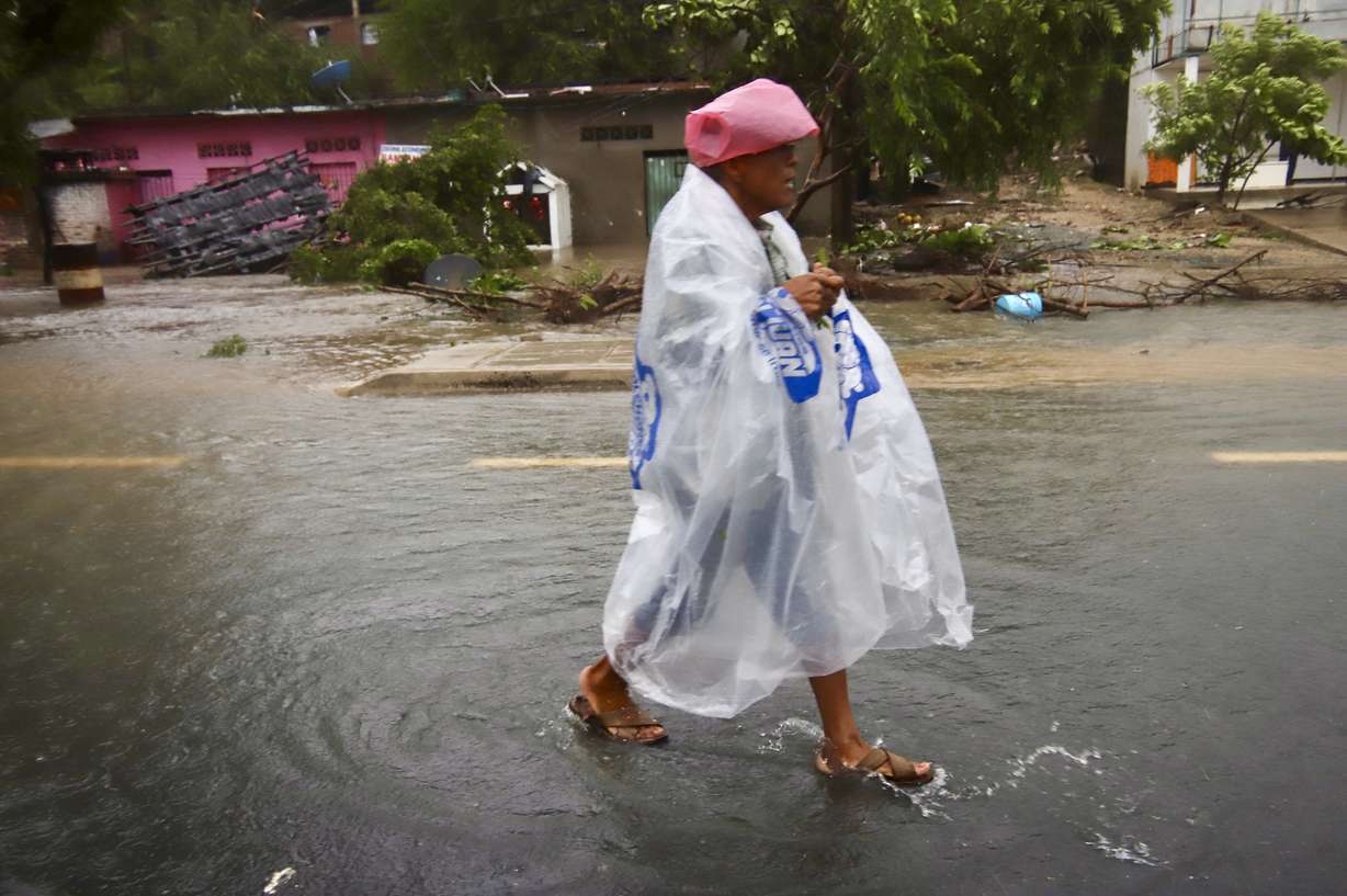 A person wearing plastic walks in the street after the passing of Hurricane John in Marquelia, Mexico, Tuesday. Helene became a hurricane Wednesday as was expected to intensify.