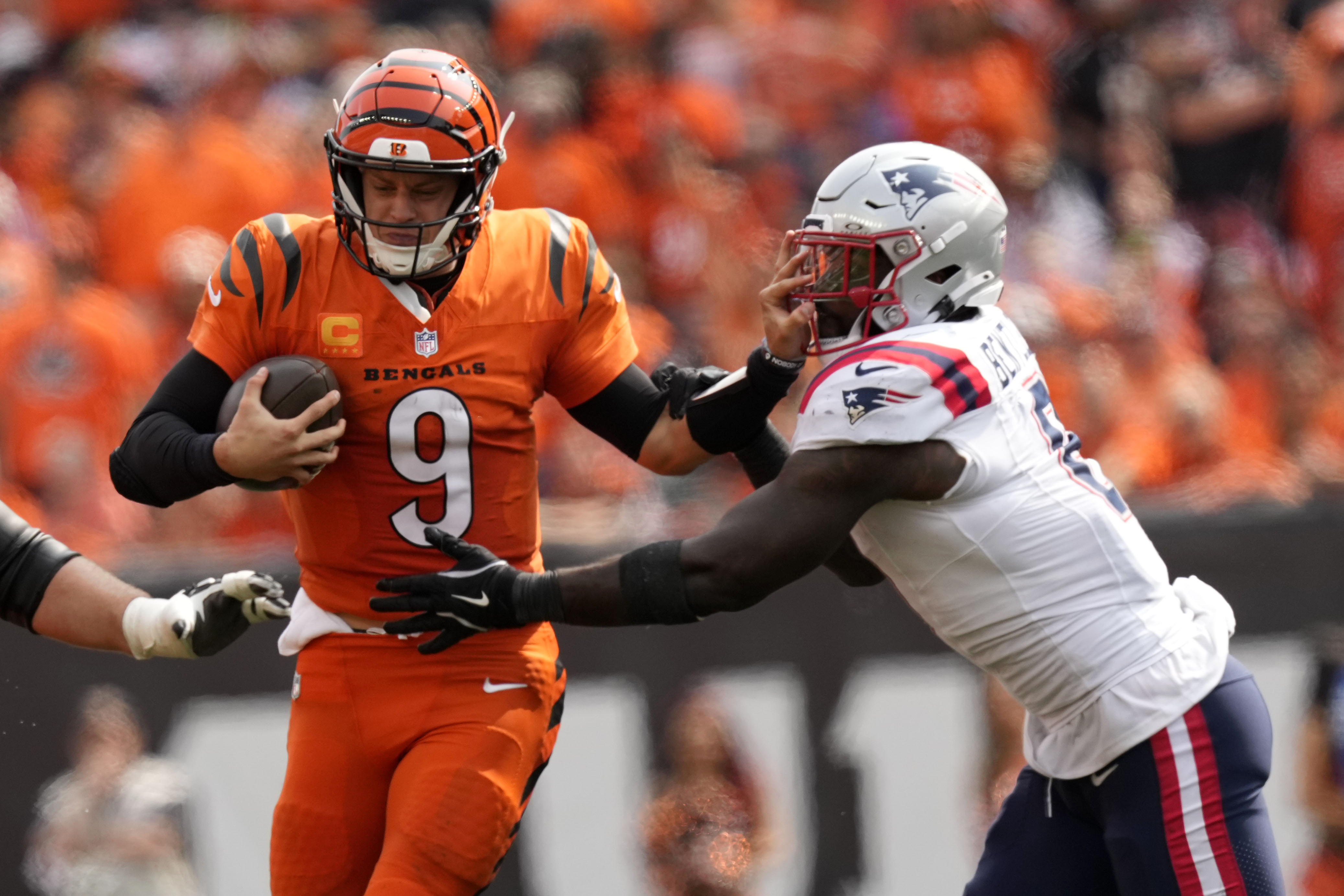 Cincinnati Bengals quarterback Joe Burrow (9) runs from New England Patriots linebacker Ja'Whaun Bentley (8) during the second half of an NFL football game, Sunday, Sept. 8, 2024, in Cincinnati. 