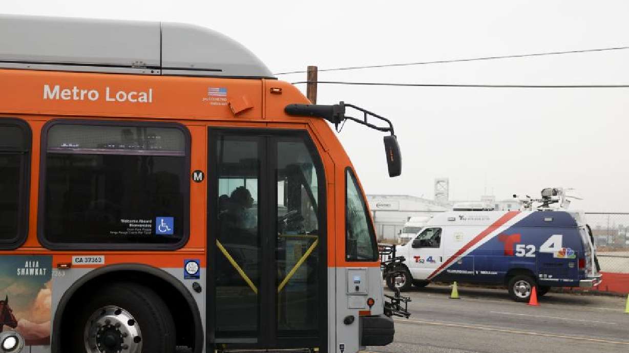 A bus passes by a news van in front of a Los Angeles bus depot near the site where overnight a bus was hijacked by an armed subject with passengers on board Wednesday in Los Angeles.
