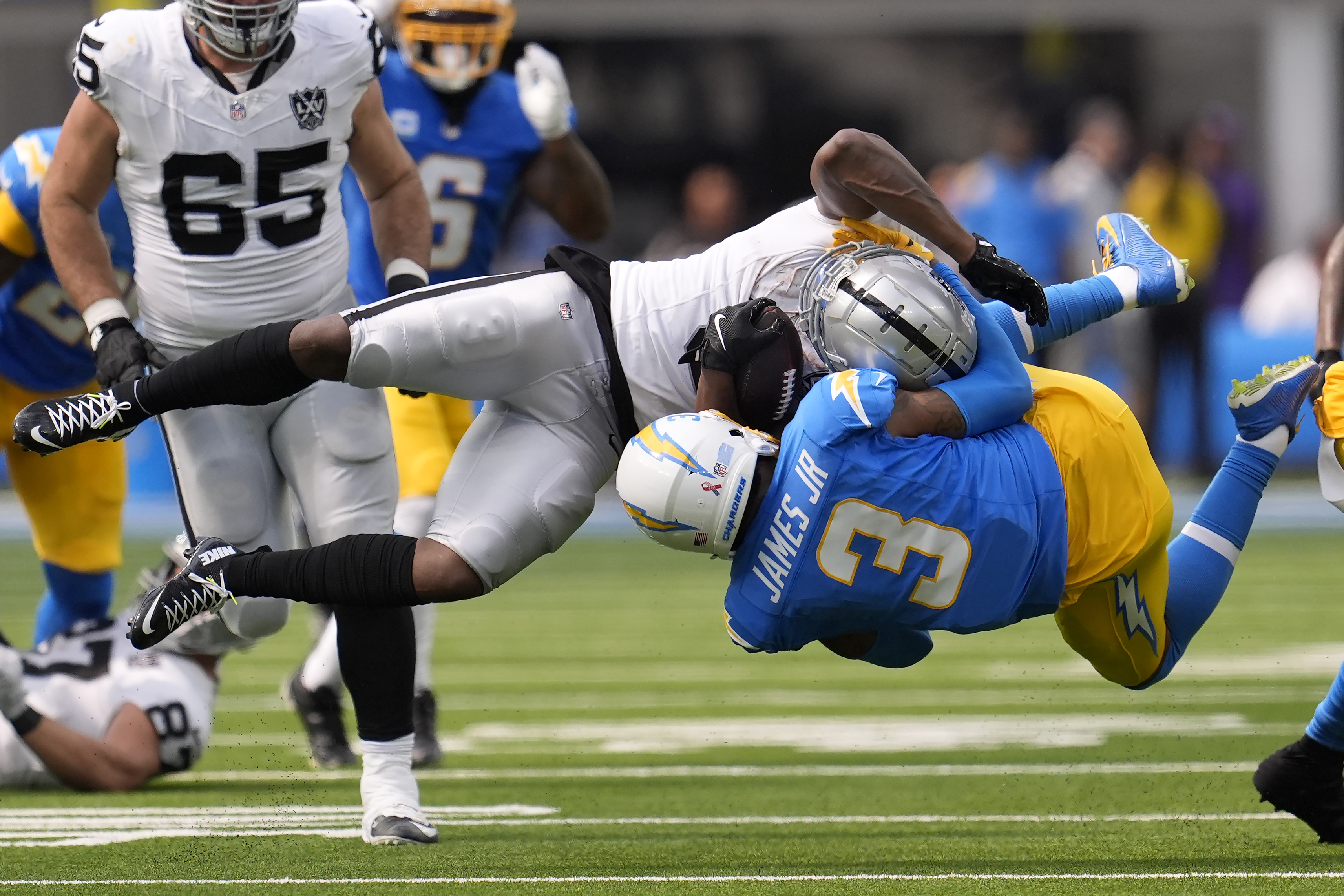 Las Vegas Raiders running back Zamir White, foreground top, is tackled by Los Angeles Chargers safety Derwin James Jr. during the second half of an NFL football game, Sunday, Sept. 8, 2024, in Inglewood, Calif. 