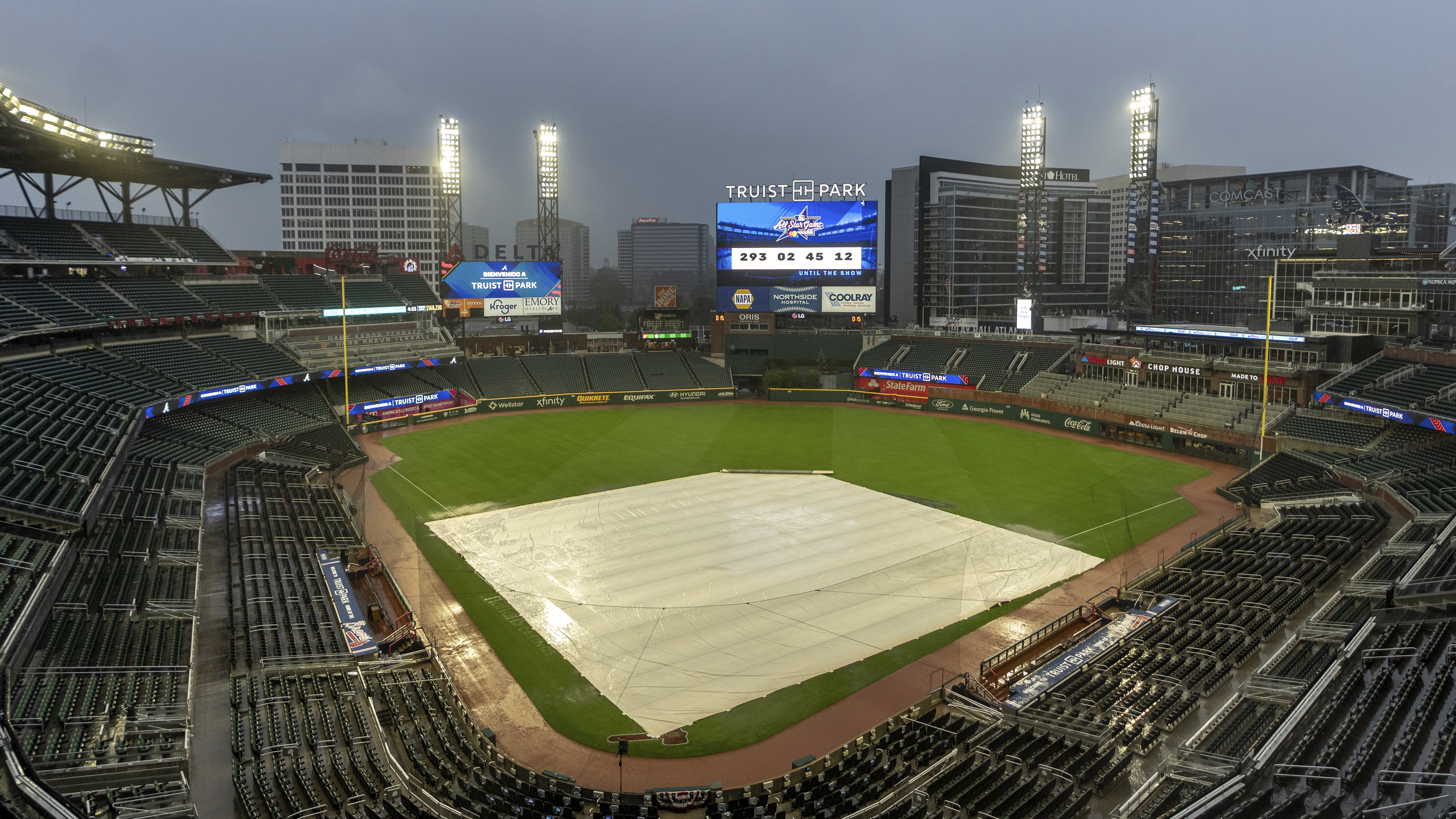 A tarp covers the infield as rain comes down at Truist Park after the baseball game between the New York Mets and Atlanta Braves as postponed, Wednesday, Sept. 25, 2024, in Atlanta. The Mets-Braves games scheduled for Wednesday and Thursday are postponed and will be made up as a doubleheader Monday, Sept. 30.