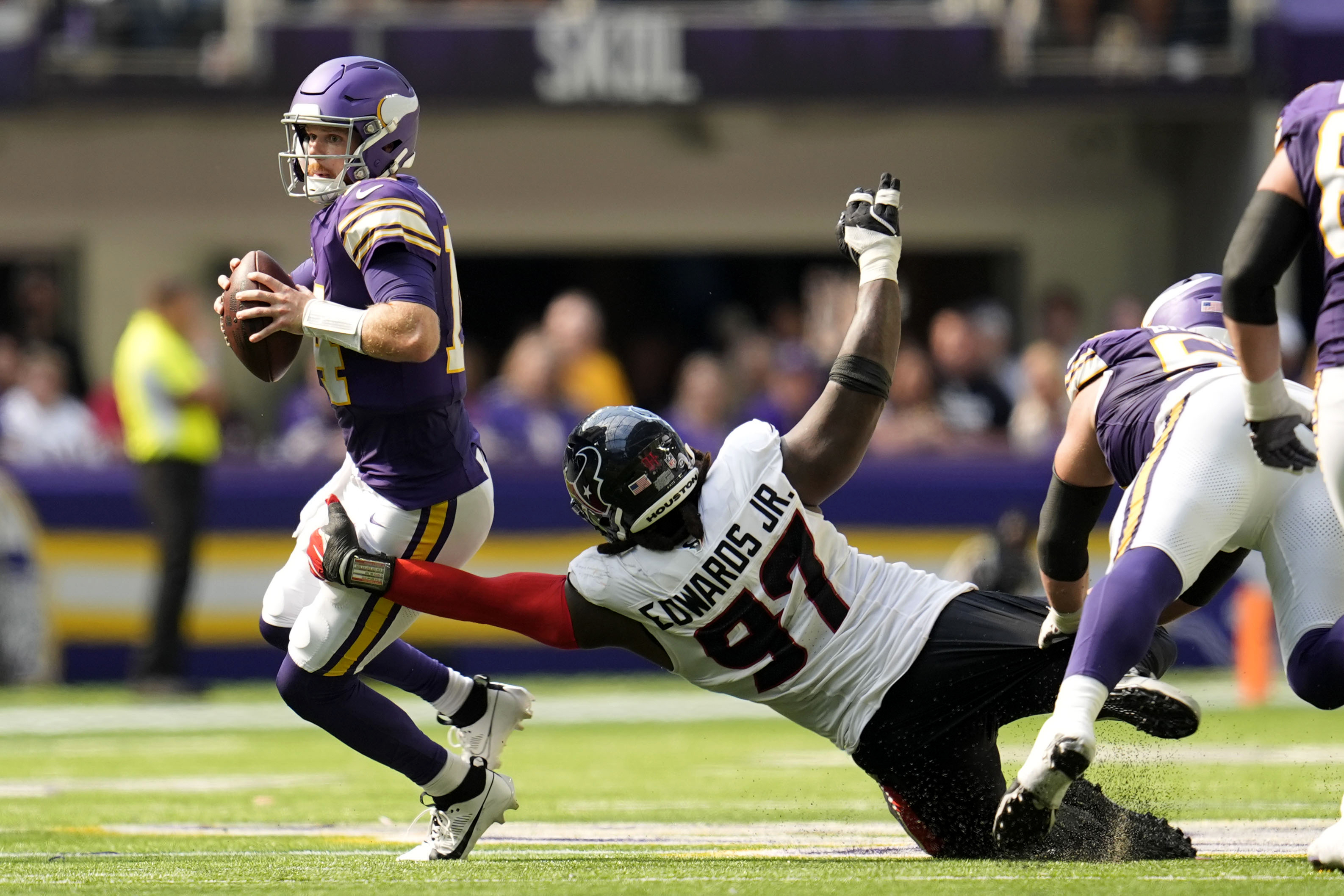 Minnesota Vikings quarterback Sam Darnold (14) looks to pass as he is pressured by Houston Texans defensive tackle Mario Edwards Jr. (97) during the second half of an NFL football game, Sunday, Sept. 22, 2024, in Minneapolis. 