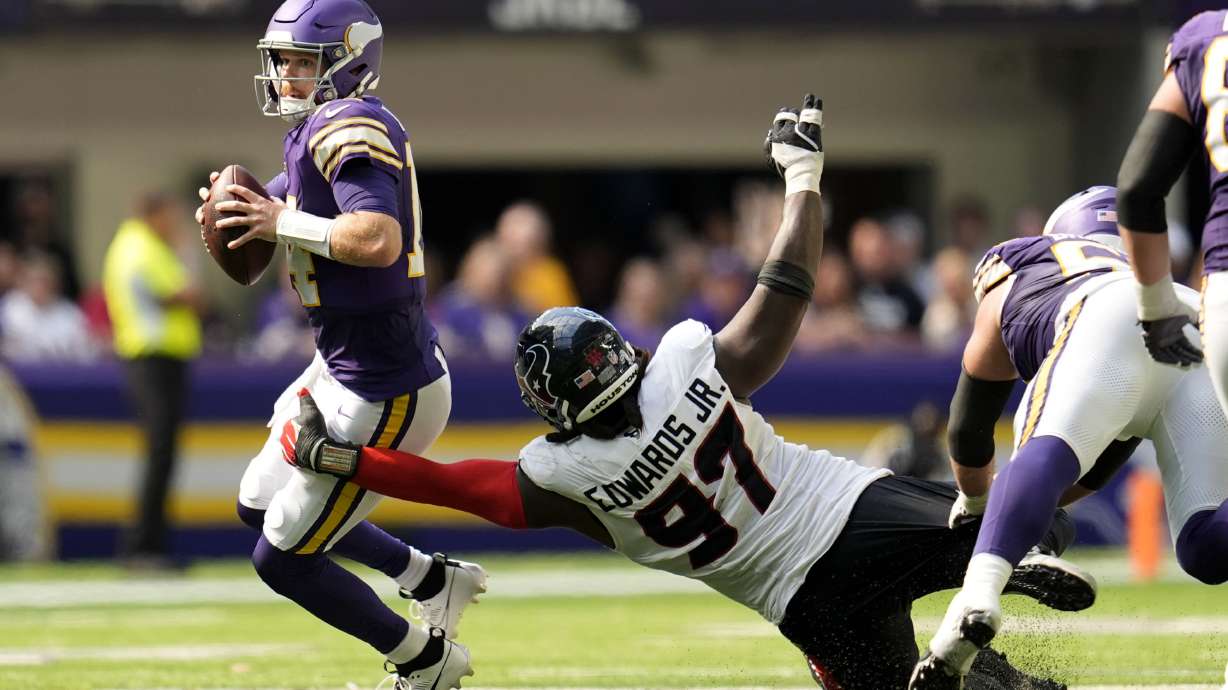 Minnesota Vikings quarterback Sam Darnold (14) looks to pass as he is pressured by Houston Texans defensive tackle Mario Edwards Jr. (97) during the second half of an NFL football game, Sunday, Sept. 22, 2024, in Minneapolis.
