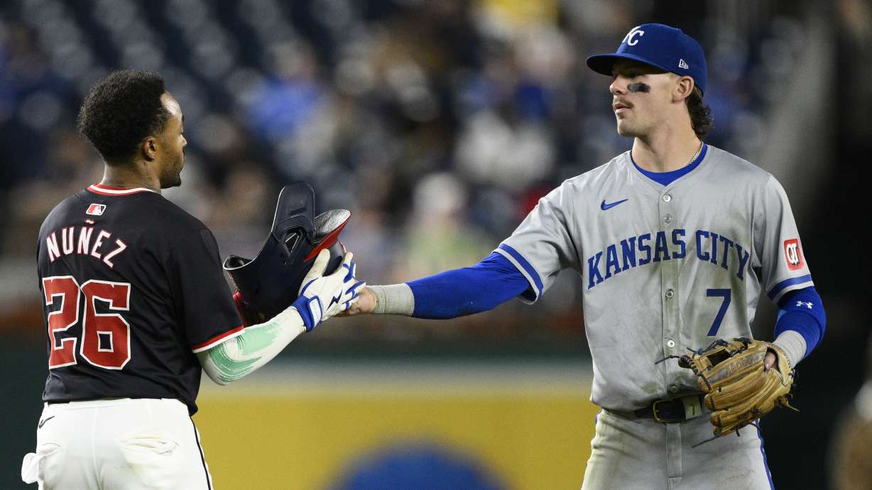 Kansas City Royals shortstop Bobby Witt Jr. (7) gives Washington Nationals' Nasim Nunez his batting helmet back during the fifth inning of a baseball game, Wednesday, Sept. 25, 2024, in Washington.