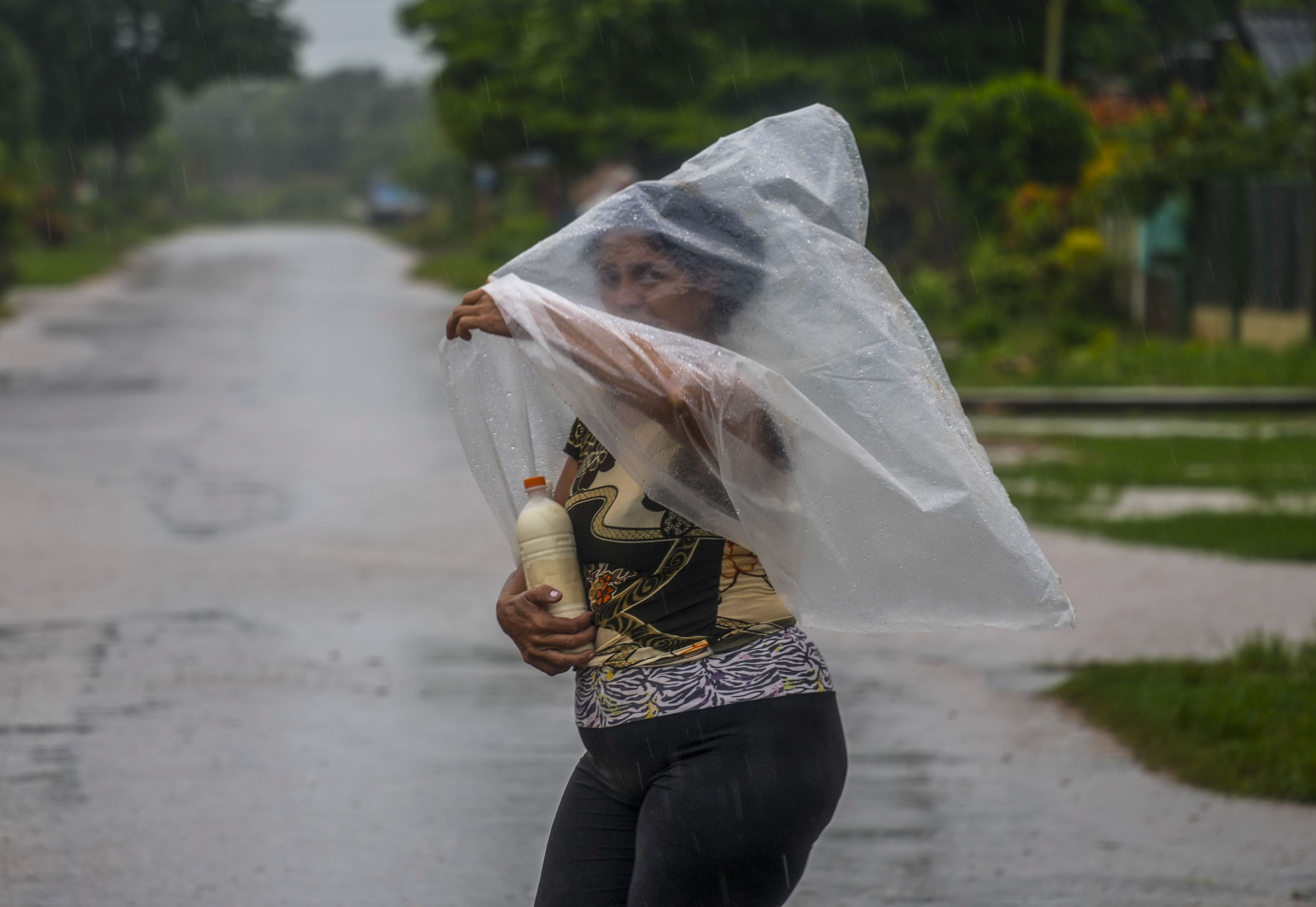 A resident uses a piece of plastic sheet as protection from heavy rains brought on by Hurricane Helene, in Batabano, Cuba, Wednesday. Helene was upgraded to a Category 4 hurricane Thursday evening.