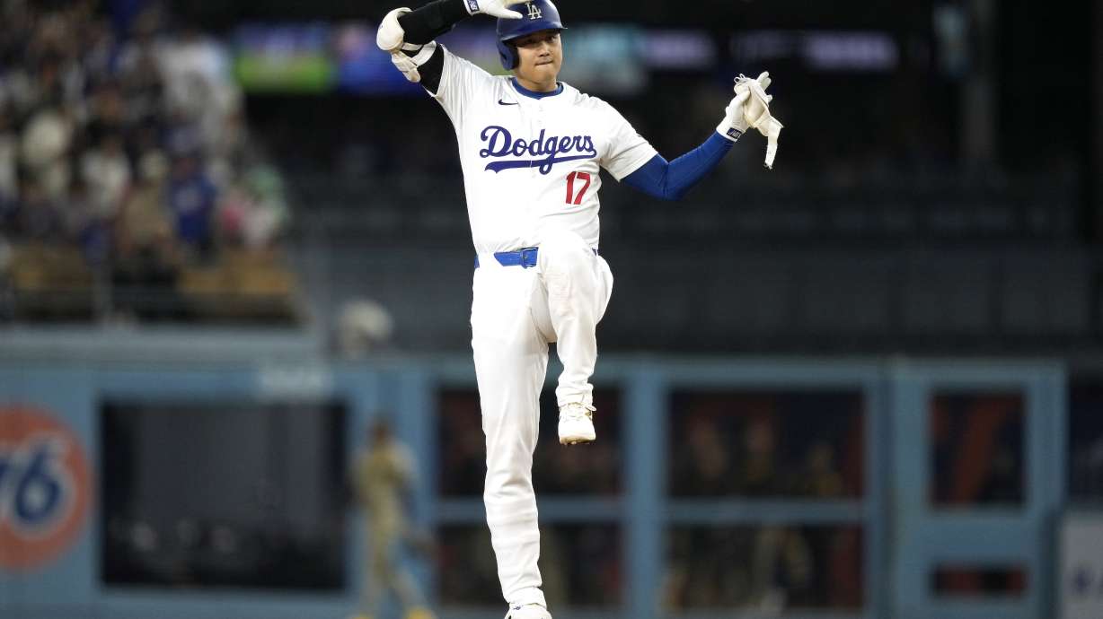 Los Angeles Dodgers' Shohei Ohtani gestures toward his dugout after hitting a double during the first inning of a baseball game against the San Diego Padres, Tuesday, Sept. 24, 2024, in Los Angeles.