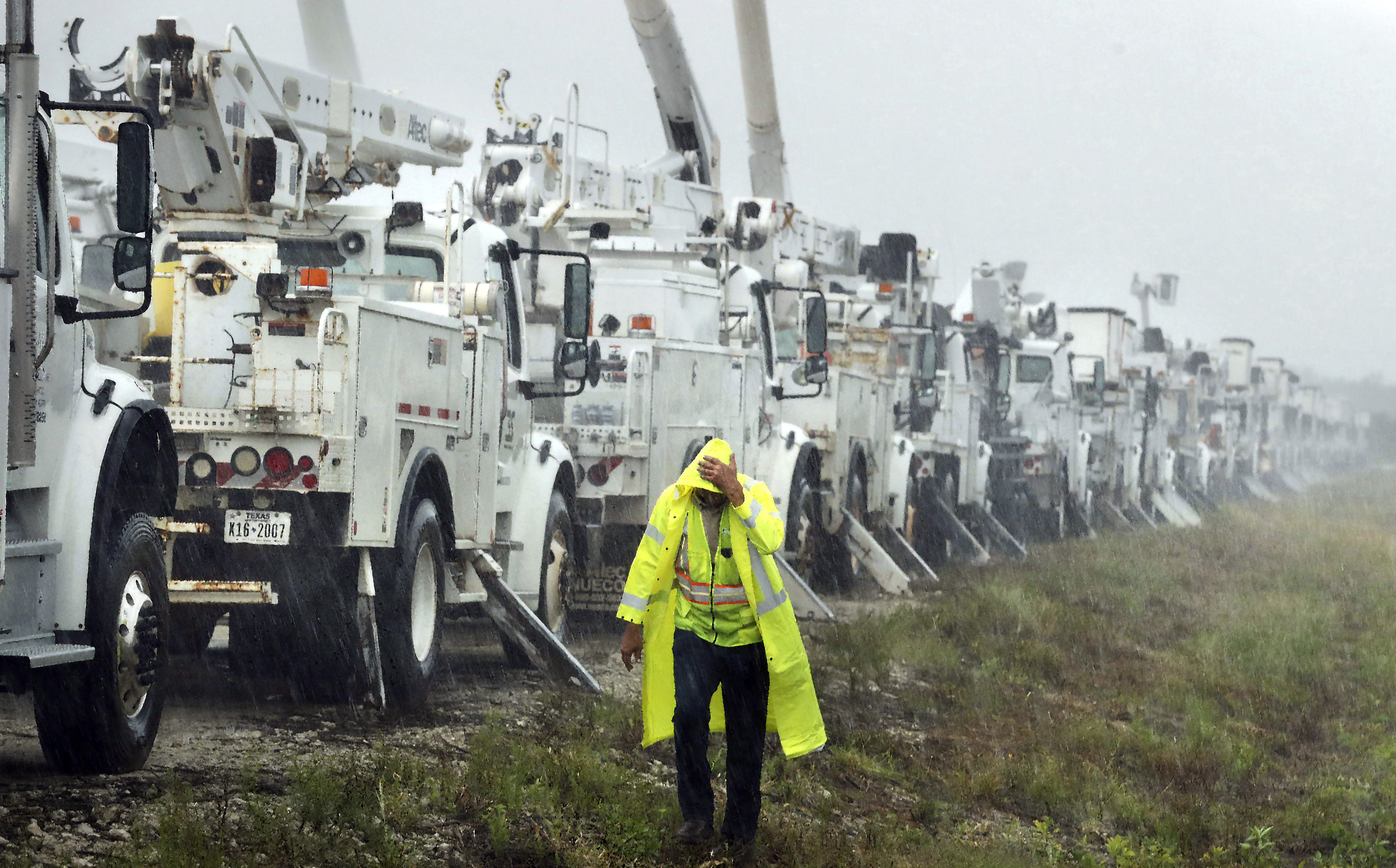 Charles Starling, a lineman with Team Fishel, is pelted with rain as he walks by a row of electrical line trucks stage in a field in The Villages, Fla., Thursday, in preparation for damage from Hurricane Helene.