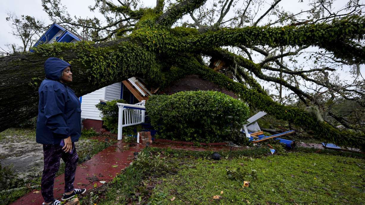 Ronda Bell looks on after an Oak tree landed on her 100-year-old home after Hurricane Helene moved through, Friday in Valdosta, Ga. The death toll has reached at least 40 across four states.