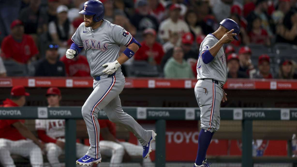 Texas Rangers designated hitter Carson Kelly, left, runs on his solo home run as third base coach Tony Beasley, right, looks on during the fourth inning of a baseball game against the Los Angeles Angels, Friday, Sept. 27, 2024, in Anaheim, Calif.