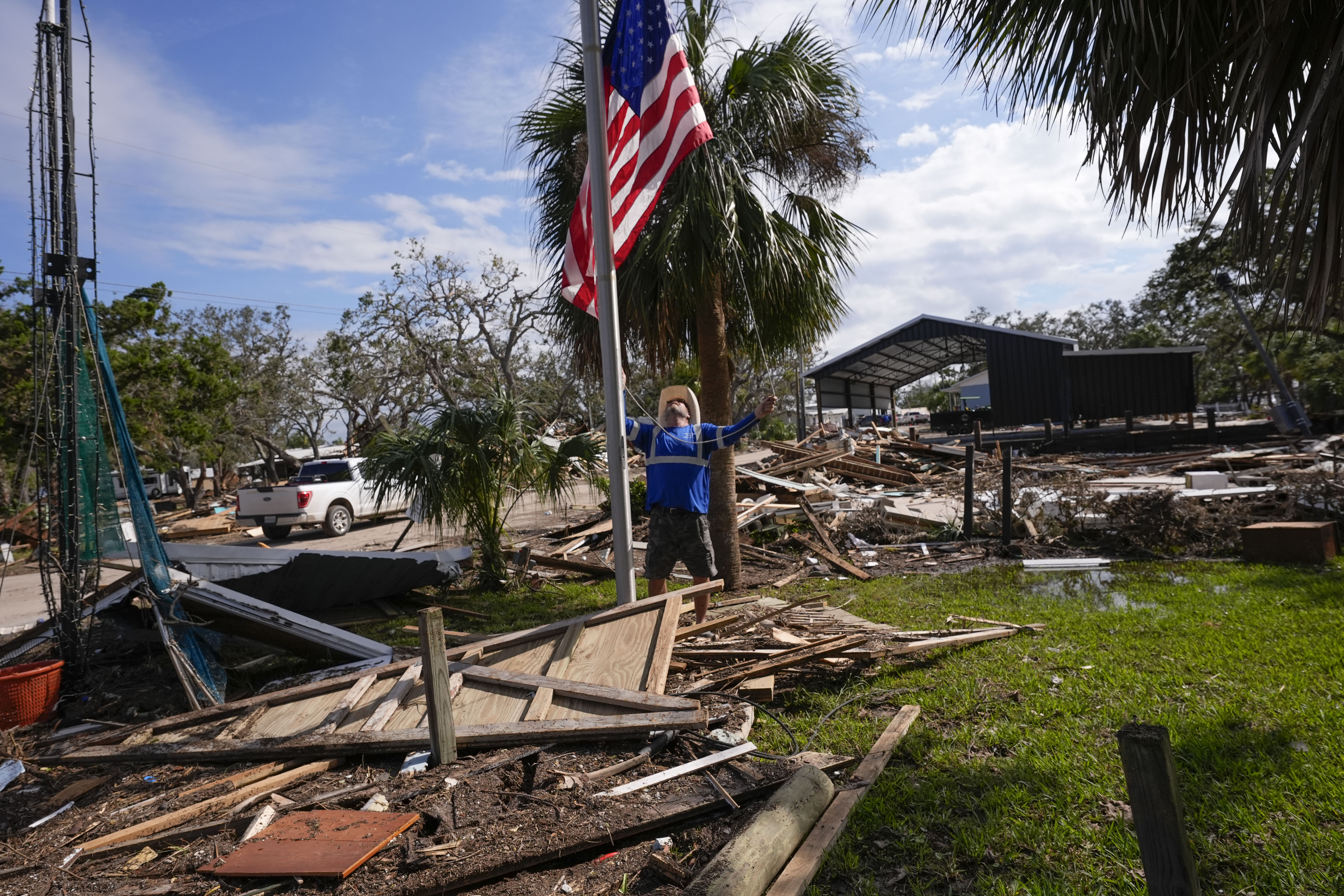 Chris Jordan, maintenance manager for Horseshoe Beach, hoists an American flag over the ruins of the city hall, in the aftermath of Hurricane Helene, in Horseshoe Beach, Fla., Saturday.
