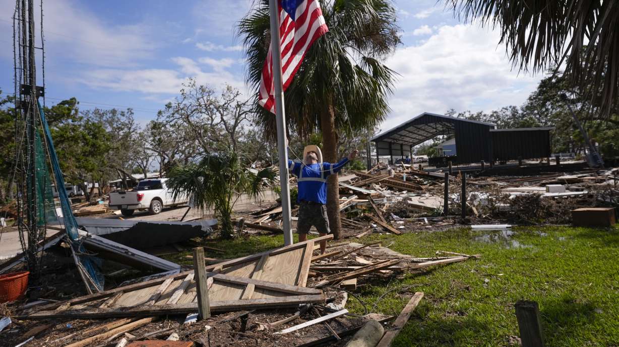 Chris Jordan, maintenance manager for Horseshoe Beach, hoists an American flag over the ruins of the city hall, in the aftermath of Hurricane Helene, in Horseshoe Beach, Fla., Saturday.