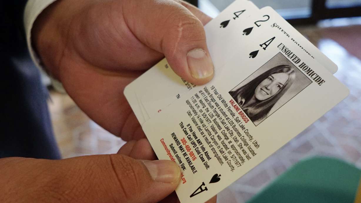Detective Jim Guzman, from the Salt Lake County Sheriff's Office, holds a deck of cards filled with the photos of victims of solved and unsolved cold cases the department is working on, during the third biannual Hope Conference in Salt Lake City on Saturday.
