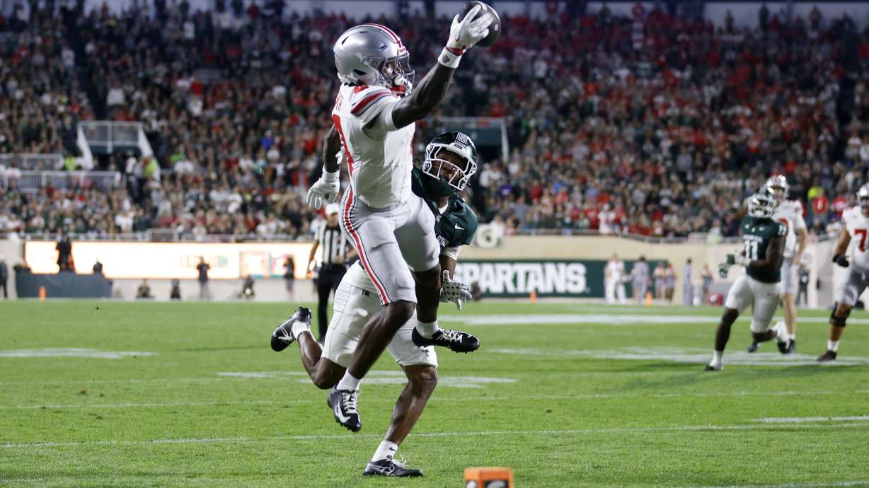 Ohio State wide receiver Jeremiah Smith, left, makes a one-handed catch for a touchdown against Michigan State defensive back Ed Woods during the first half of an NCAA college football game, Saturday, Sept. 28, 2024, in East Lansing, Mich.