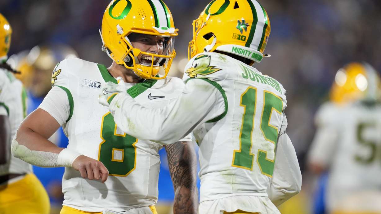 Oregon quarterback Dillon Gabriel, left, celebrates after throwing a touchdown pass to wide receiver Tez Johnson (15) during the first half of an NCAA college football game against UCLA, Saturday, Sept. 28, 2024, in Pasadena, Calif.