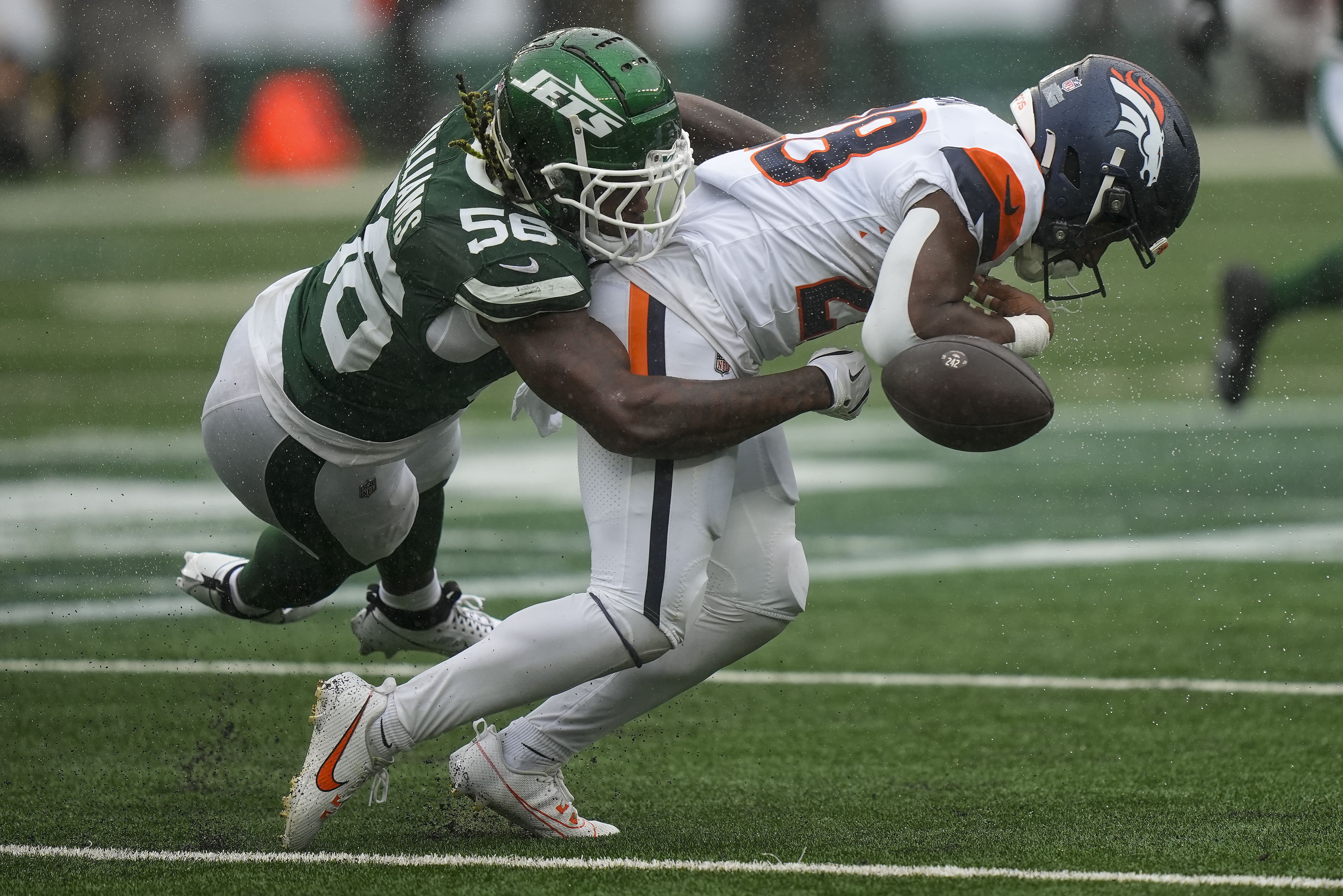 New York Jets linebacker Quincy Williams (56) knocks the ball loose for a fumble by Denver Broncos running back Tyler Badie (28) during the first quarter of an NFL football game, Sunday, Sept. 29, 2024, in East Rutherford, N.J.