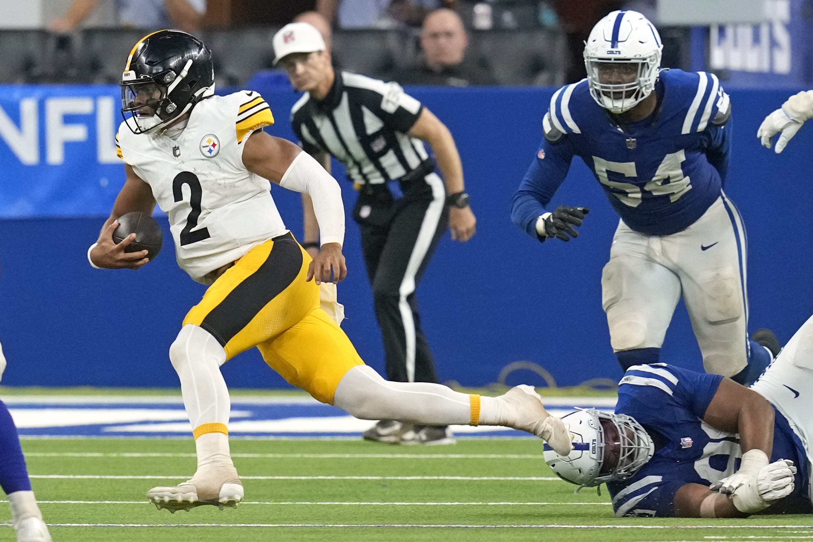 Pittsburgh Steelers quarterback Justin Fields (2) scrambles past a tackle-attempt by Indianapolis Colts defensive end Tyquan Lewis, lower right, during the second half of an NFL football game Sunday, Sept. 29, 2024, in Indianapolis. 