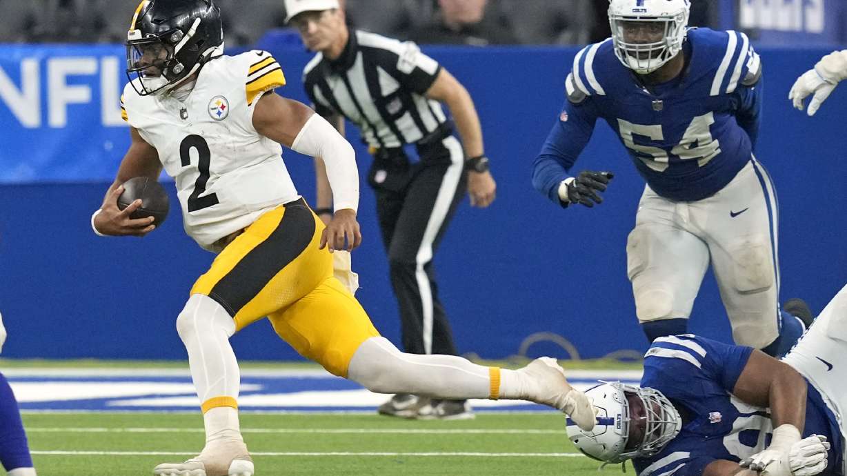 Pittsburgh Steelers quarterback Justin Fields (2) scrambles past a tackle-attempt by Indianapolis Colts defensive end Tyquan Lewis, lower right, during the second half of an NFL football game Sunday, Sept. 29, 2024, in Indianapolis.