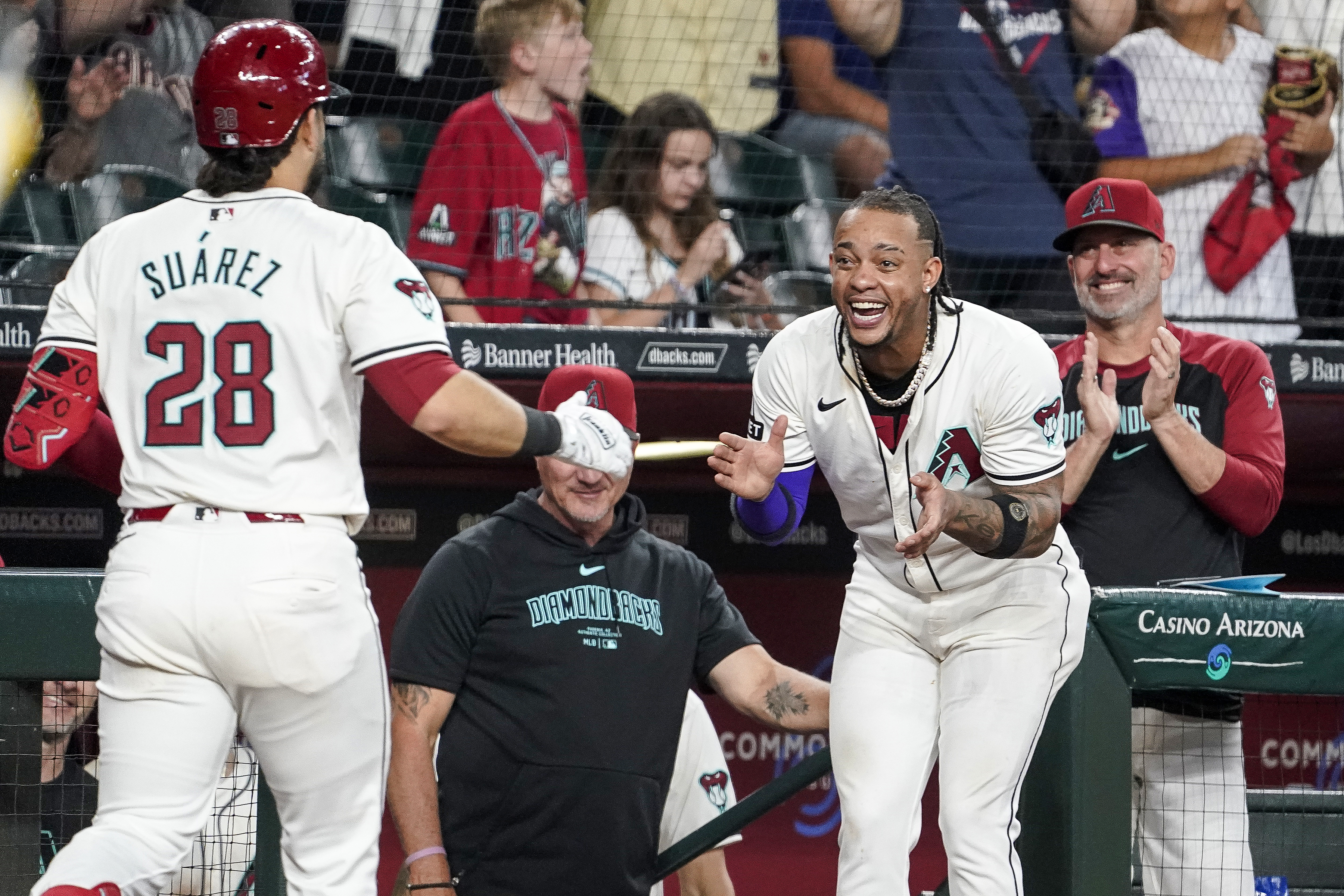 Arizona Diamondbacks' Ketel Marte, right, and manager Torey Lovullo, far right, greets Eugenio Suárez after Suárez's home run against the San Diego Padres during the seventh inning of a baseball game, Sunday, Sept. 29, 2024, in Phoenix.