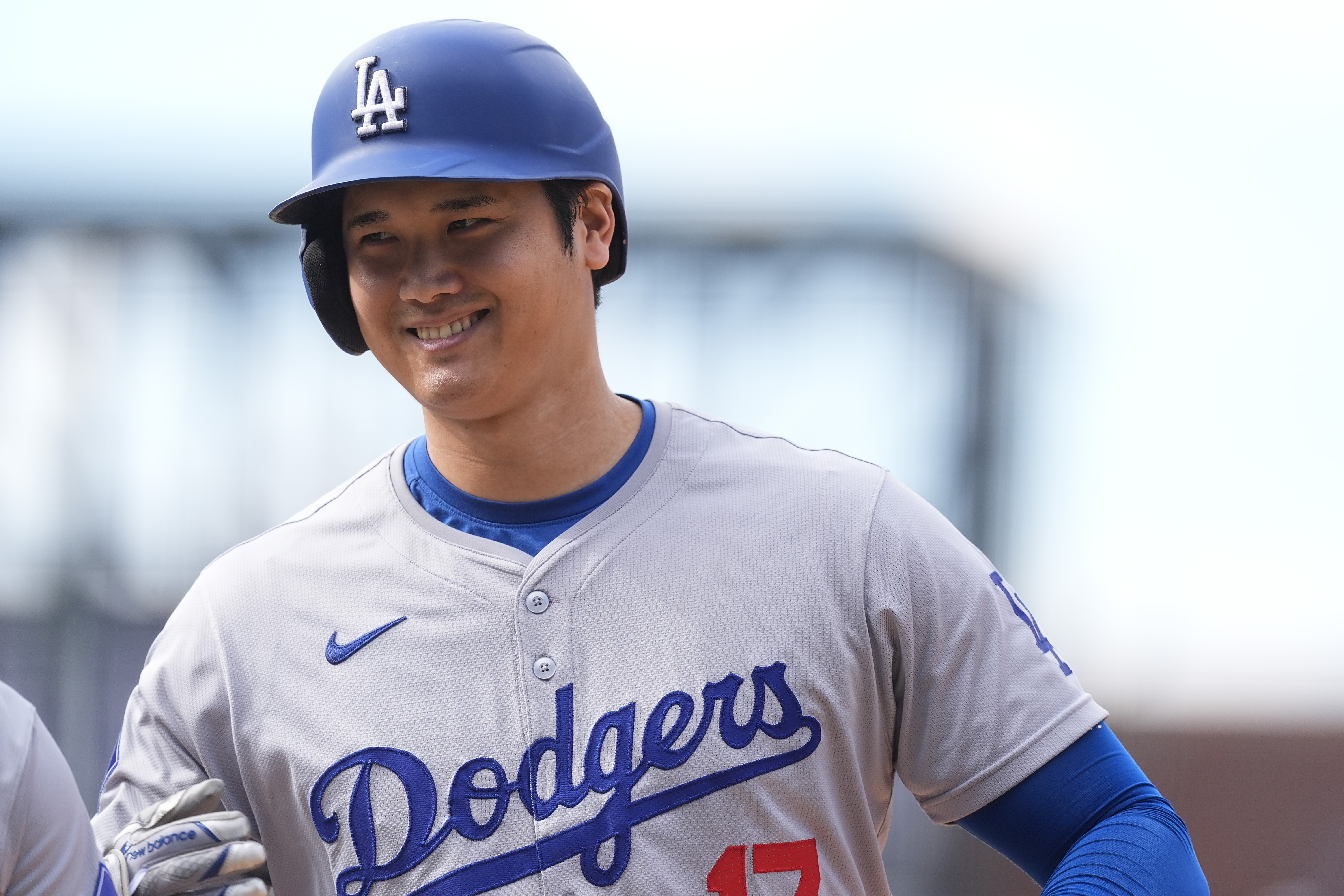 Los Angeles Dodgers' Shohei Ohtani smiles after reaching first base on a single off Colorado Rockies relief pitcher Seth Halvorsen in the eighth inning of a baseball game Sunday, Sept. 29, 2024, in Denver. 