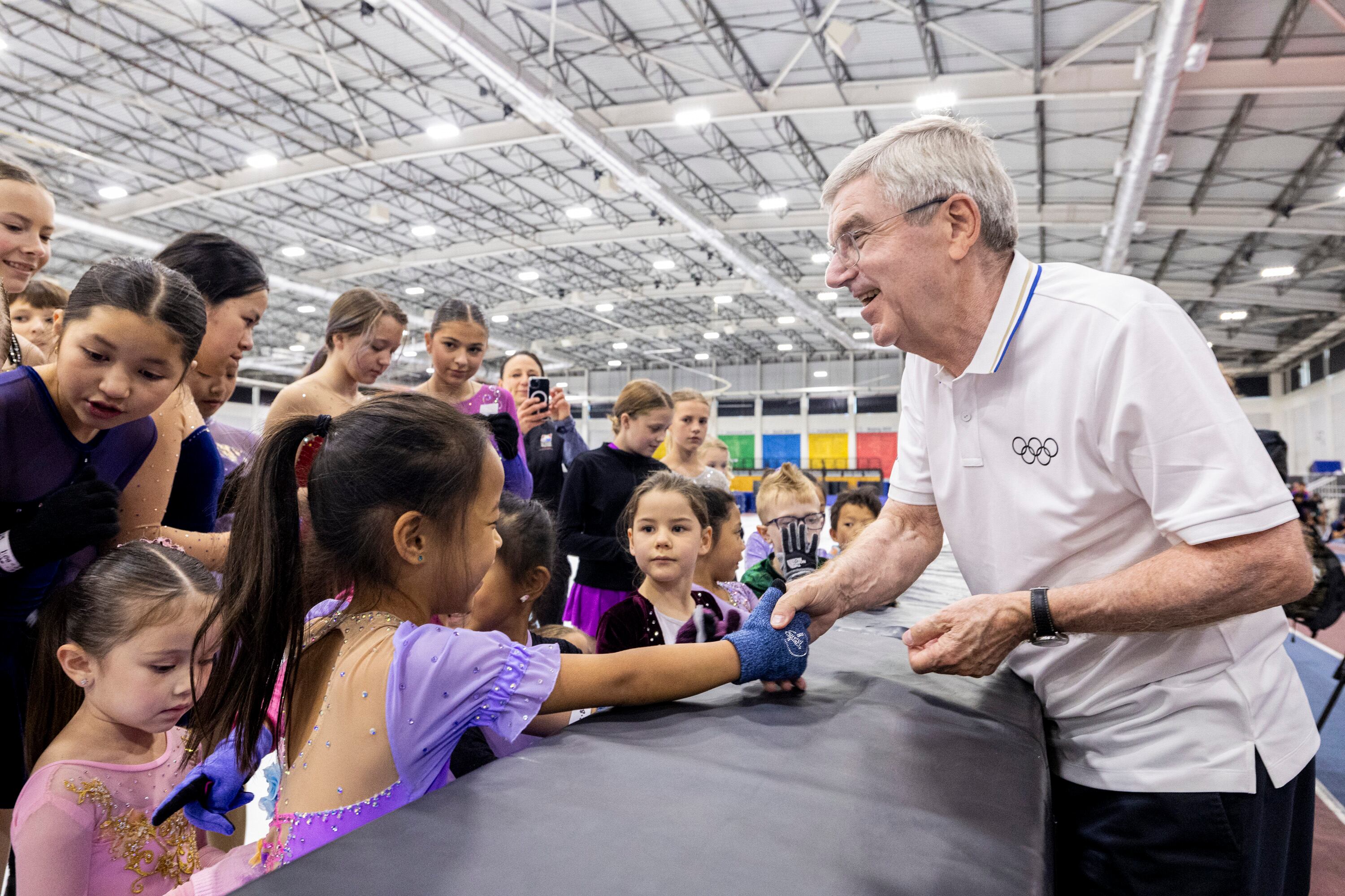 International Olympic Committee President Thomas Bach gives out Olympic pins as he talks with youth figure skaters at the Utah Olympic Oval in Kearns on Saturday.