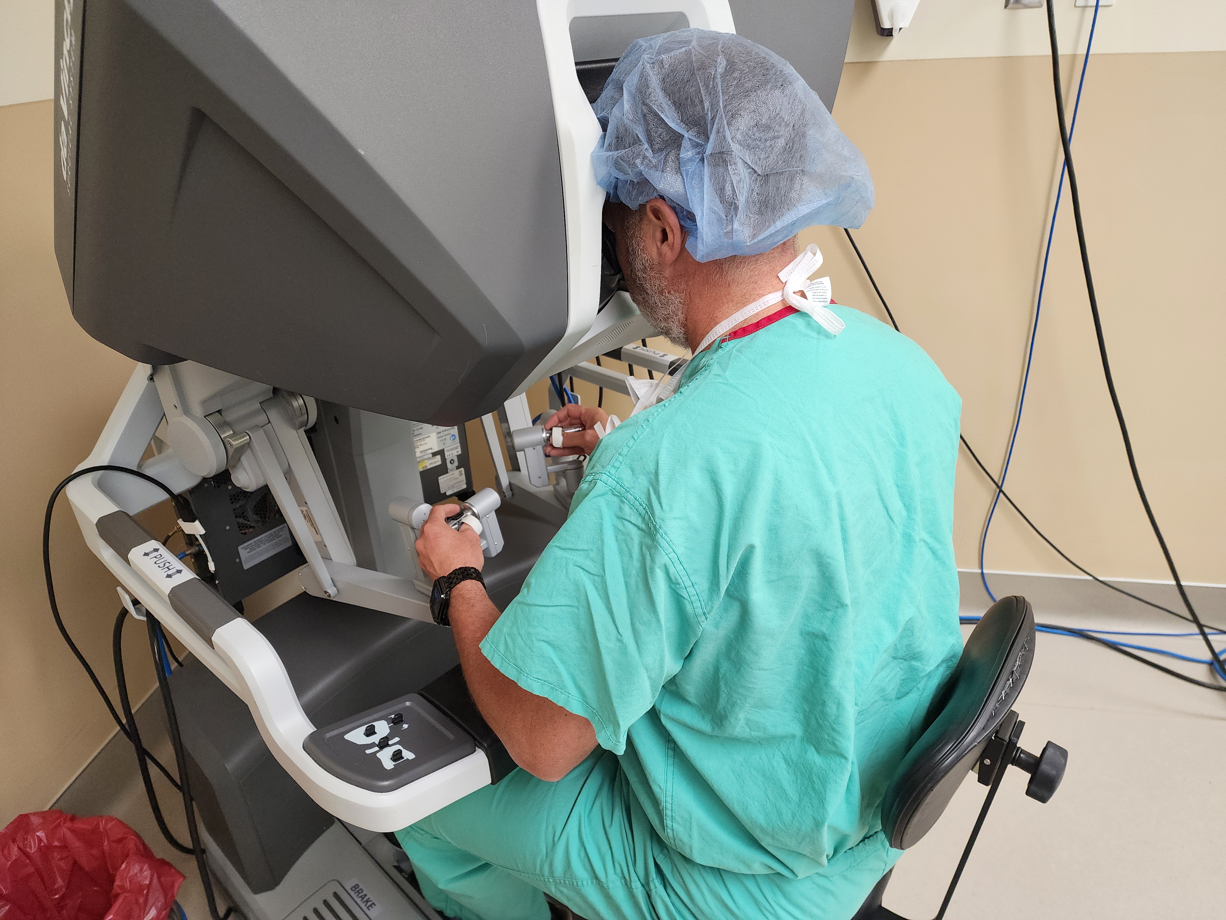 Dr. Richard Rassmussen, of Utah Surgical Associates and the bariatric surgery director at Intermountain's Utah Valley Hospital, at the robotic surgical console. If his forehead loses contact with a depressed switch, everything stops.