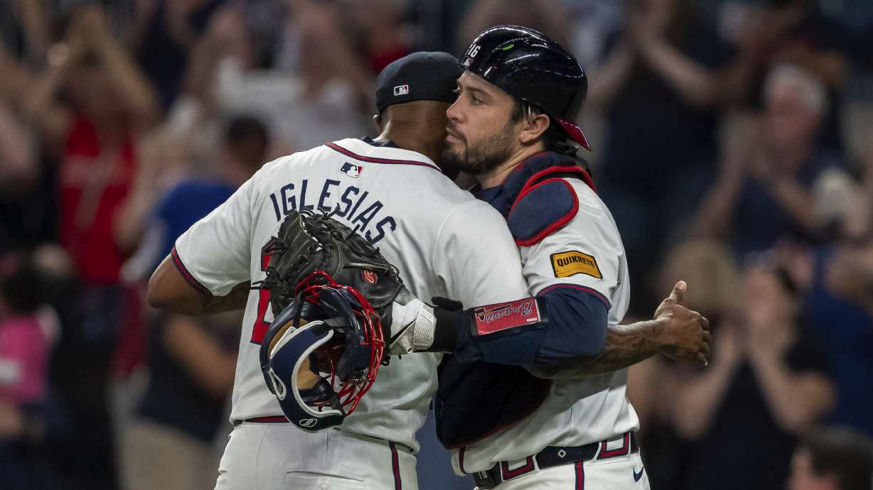 Atlanta Braves pitcher Raisel Iglesias, left, celebrates the win with catcher Travis d'Arnaud, right, following the ninth inning of a baseball game against the New York Mets, Tuesday, Sept. 24, 2024, in Atlanta.