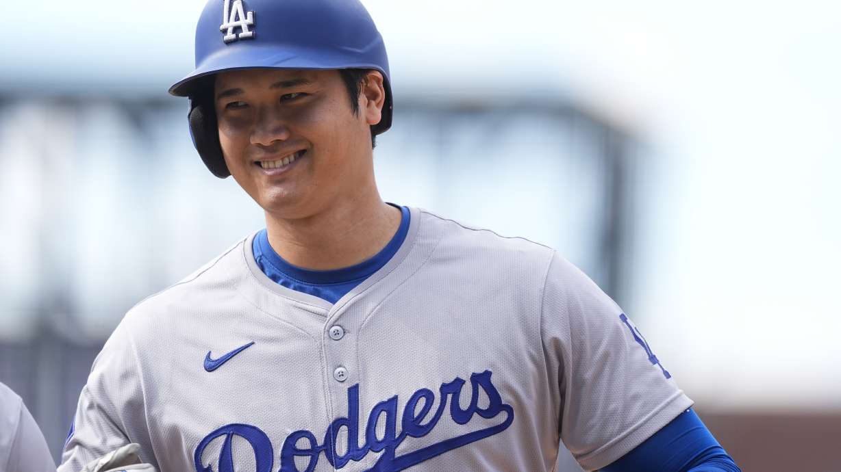 Los Angeles Dodgers' Shohei Ohtani smiles after reaching first base on a single off Colorado Rockies relief pitcher Seth Halvorsen in the eighth inning of a baseball game Sunday, Sept. 29, 2024, in Denver.