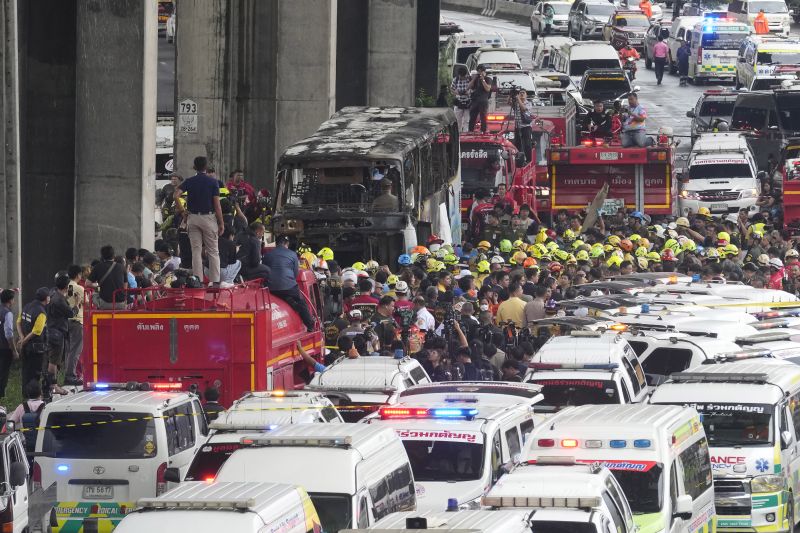 Rescuers gather at the site of a bus that caught fire, carrying young students with their teachers, in suburban Bangkok, Thailand, Tuesday.