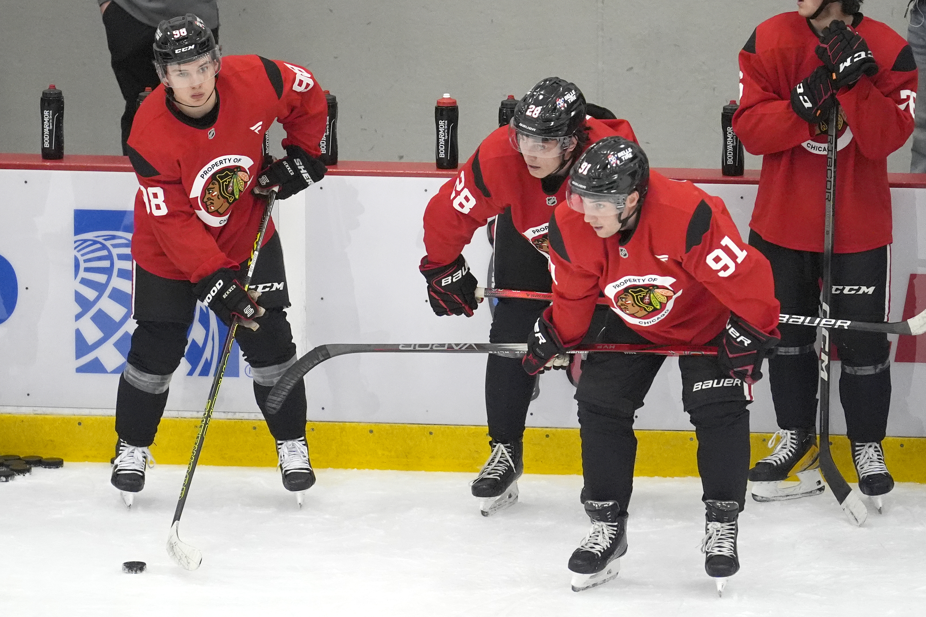 Chicago Blackhawks' Connor Bedard, left, handles the puck as teammates Colton Dach (28) and Frank Nazar also participate in the team's NHL hockey training camp Thursday, Sept. 19, 2024, in Chicago.