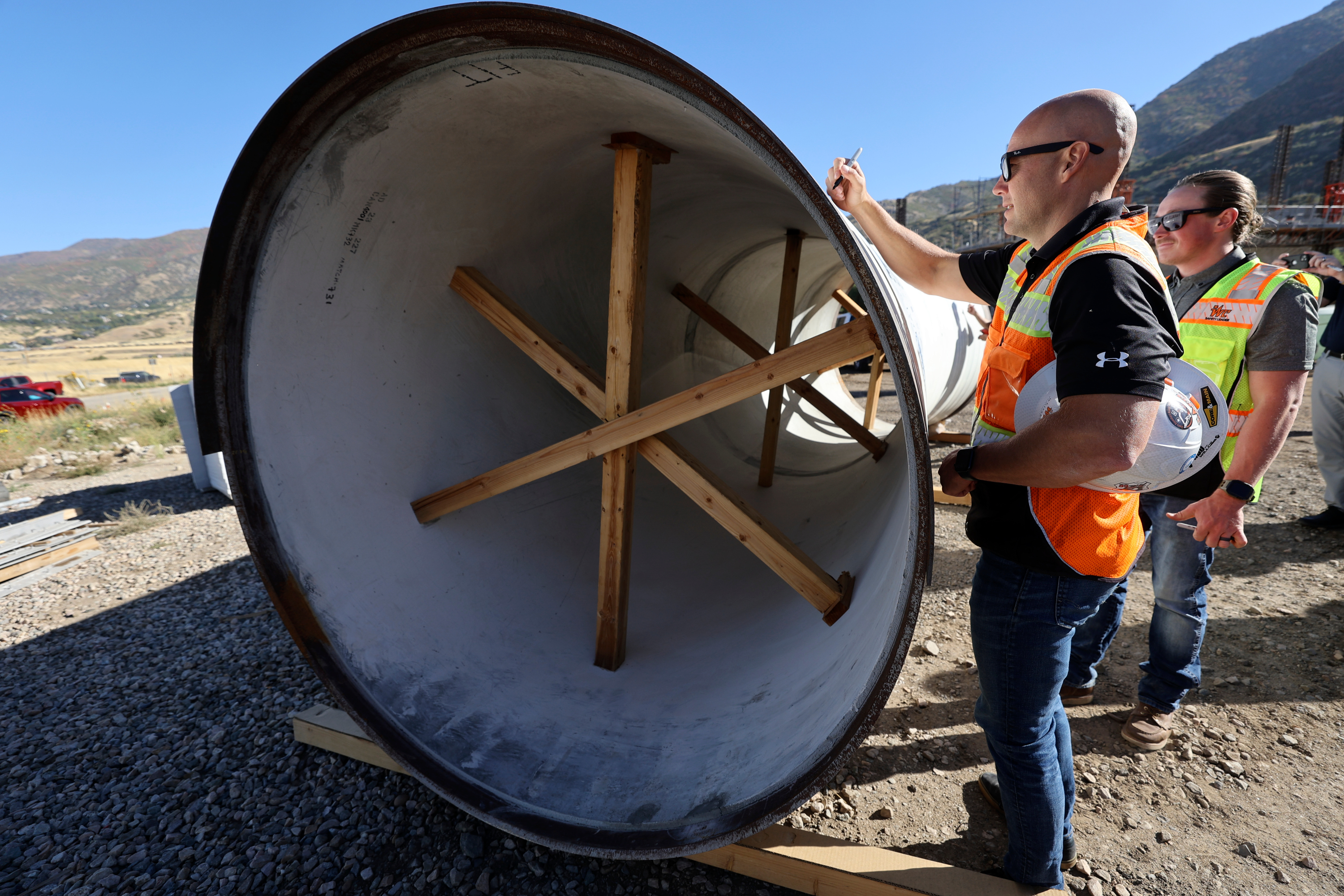 Sage Thorpe signs a 72-inch steel pipe that will be installed as part of an $81-million seismic resilience project for the Davis Aqueduct, to increase water security in the event of a major earthquake, in South Weber on Wednesday. 